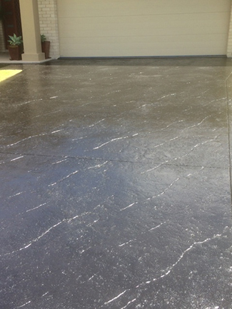 Glossy Black Concrete Driveway With White Vein-like Markings, in Front of a Garage — Williams Concreting In Old Bar, NSW