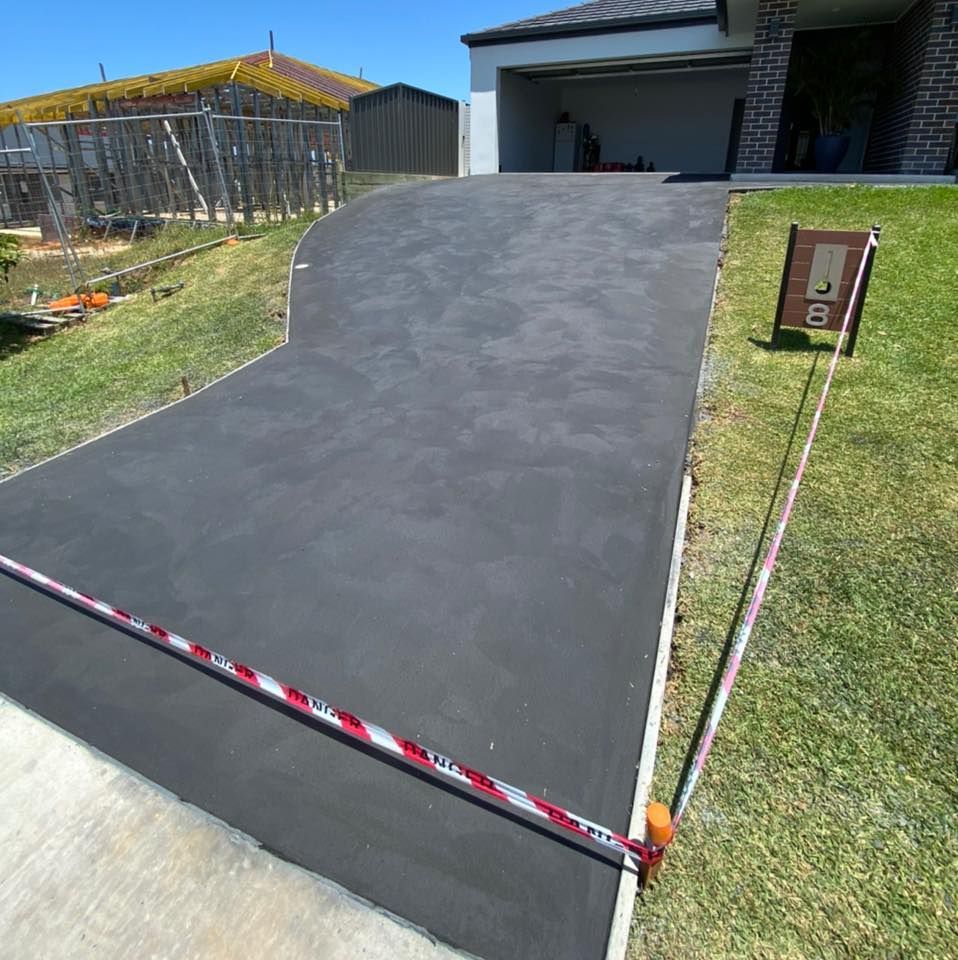 Asphalt Driveway Leading to a Modern House, Bordered by Grass and a Street Number Sign — Williams Concreting In Taree, NSW