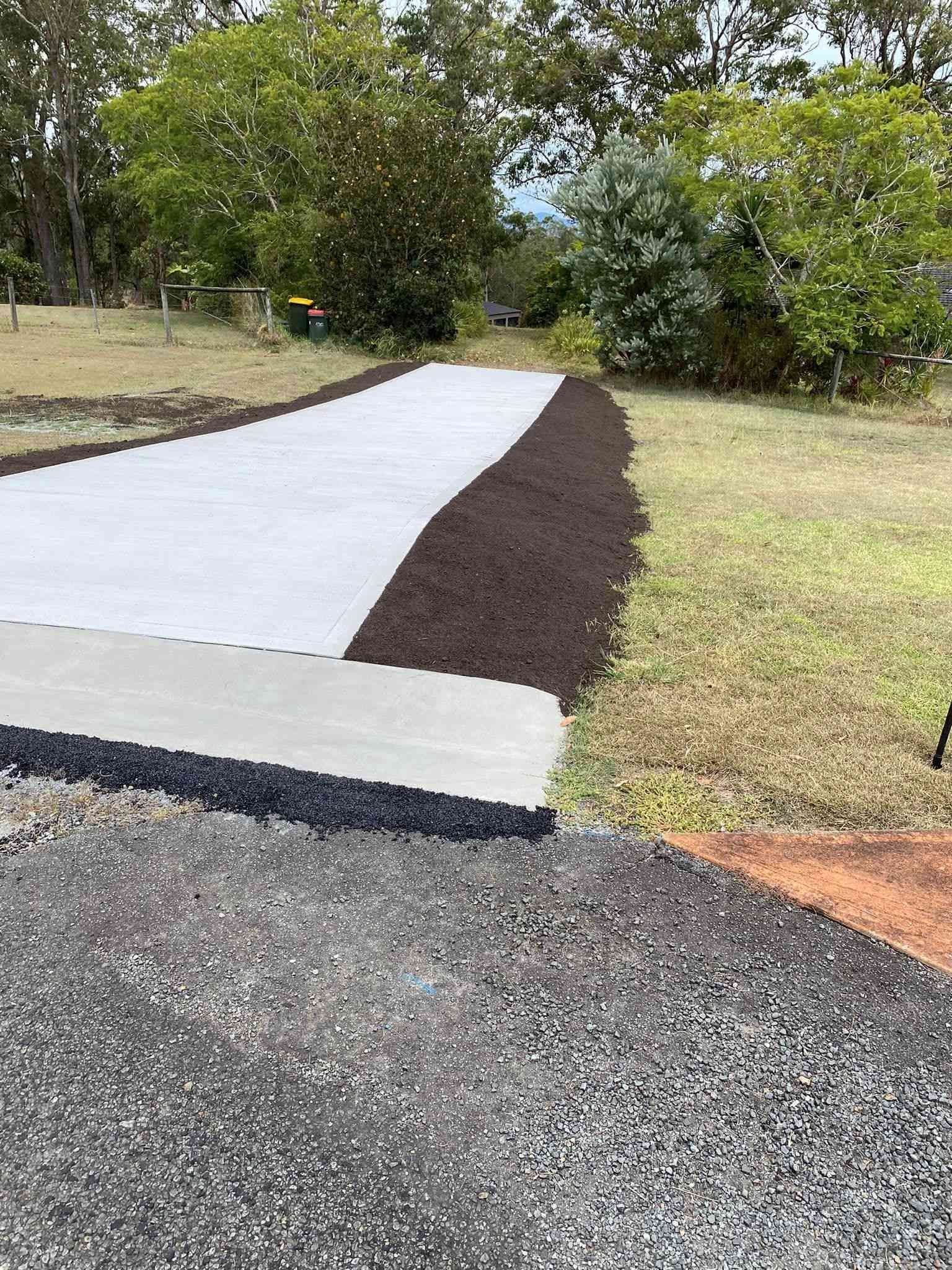 Concrete Driveway With Mulch Border, Leading Towards a Grassy Area With Trees — Williams Concreting In Harrington, NSW