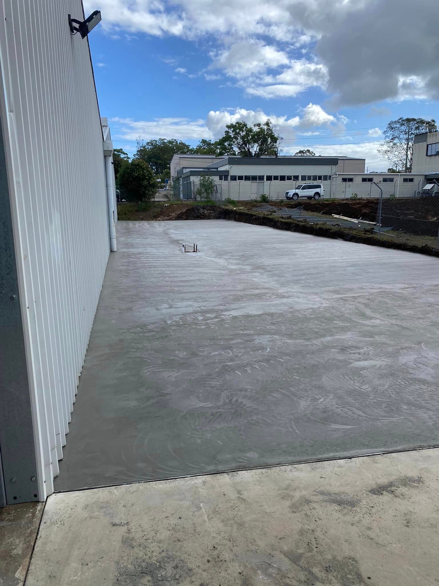 Newly Poured Concrete Slab Next to a White Wall — Williams Concreting In Taree, NSW