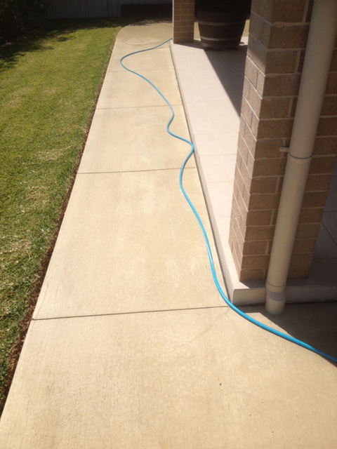 Concrete Walkway With a Blue Hose Running Along It — Williams Concreting In Harrington, NSW
