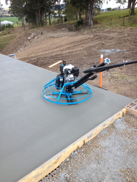 A Power Trowel Smoothing a Fresh Concrete Slab Outdoors; Blue Machine, Gray Surface — Williams Concreting In Taree, NSW
