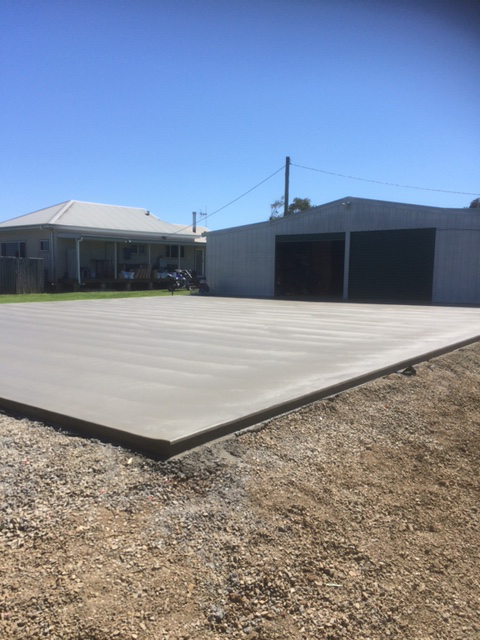 A Newly Poured Concrete Slab in Front of a House and a Shed — Williams Concreting In Wingham, NSW