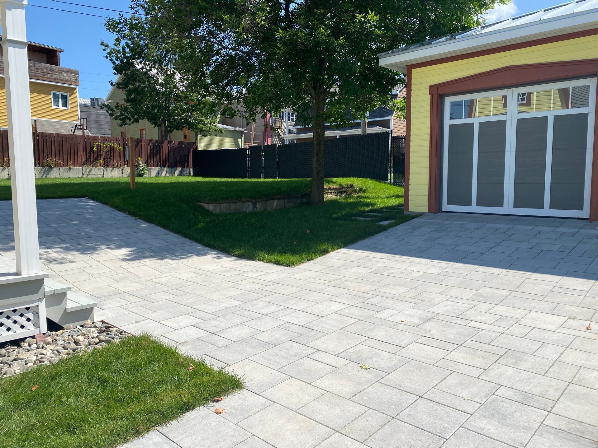 Une allée menant à un garage avec une maison jaune en arrière-plan