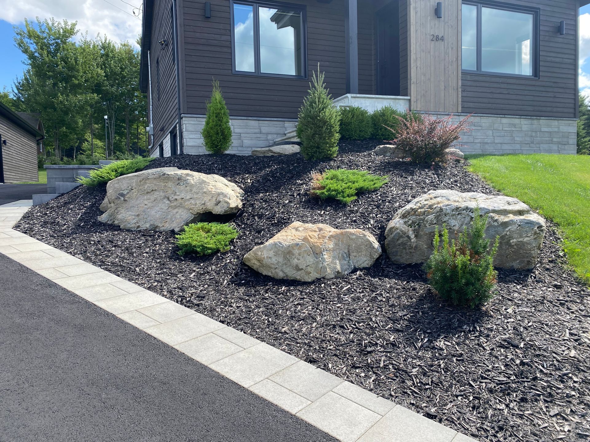 Un jardin avec des rochers et des plantes devant une maison.