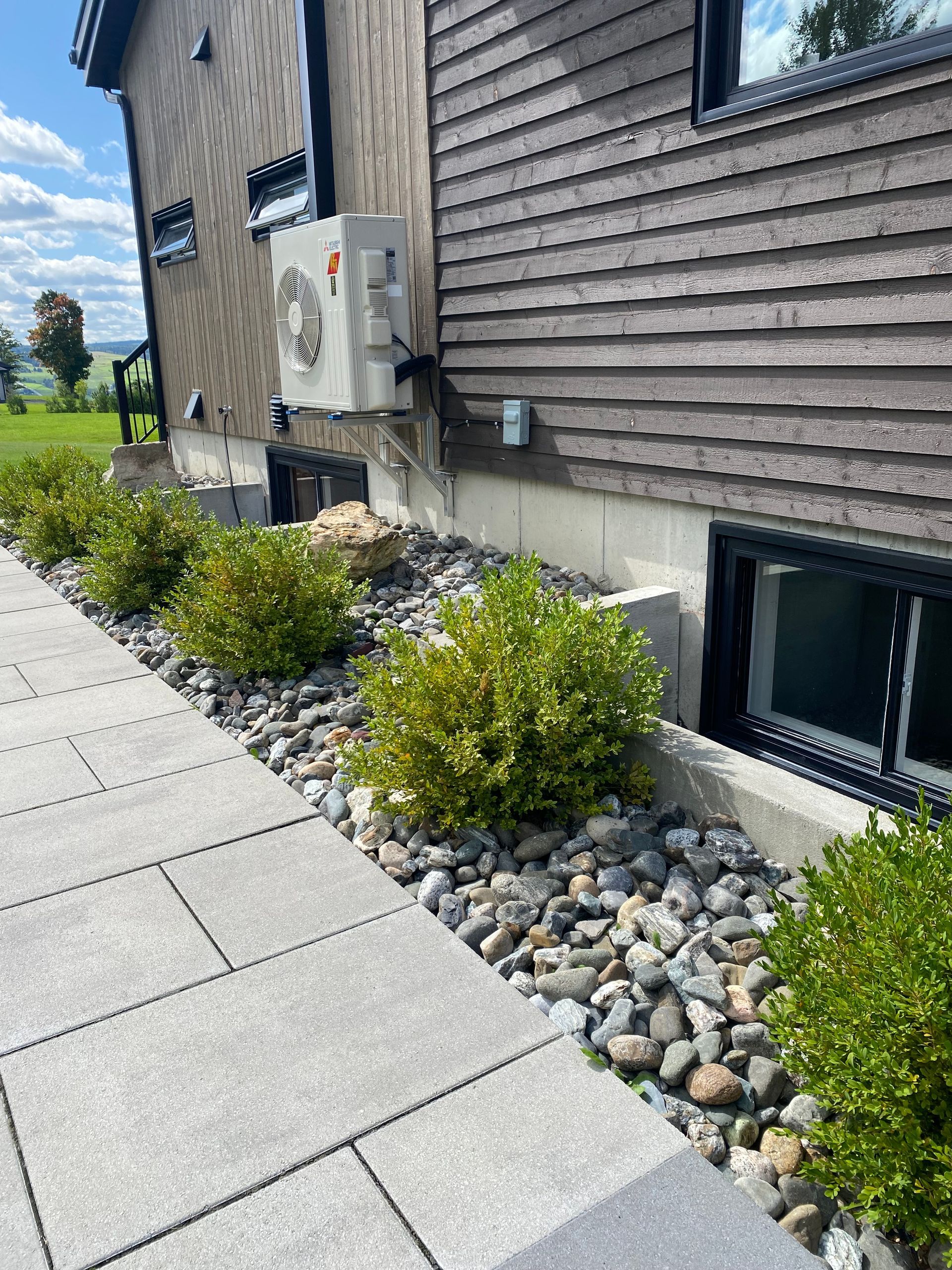 Un trottoir menant à une maison avec beaucoup de plantes et de rochers.
