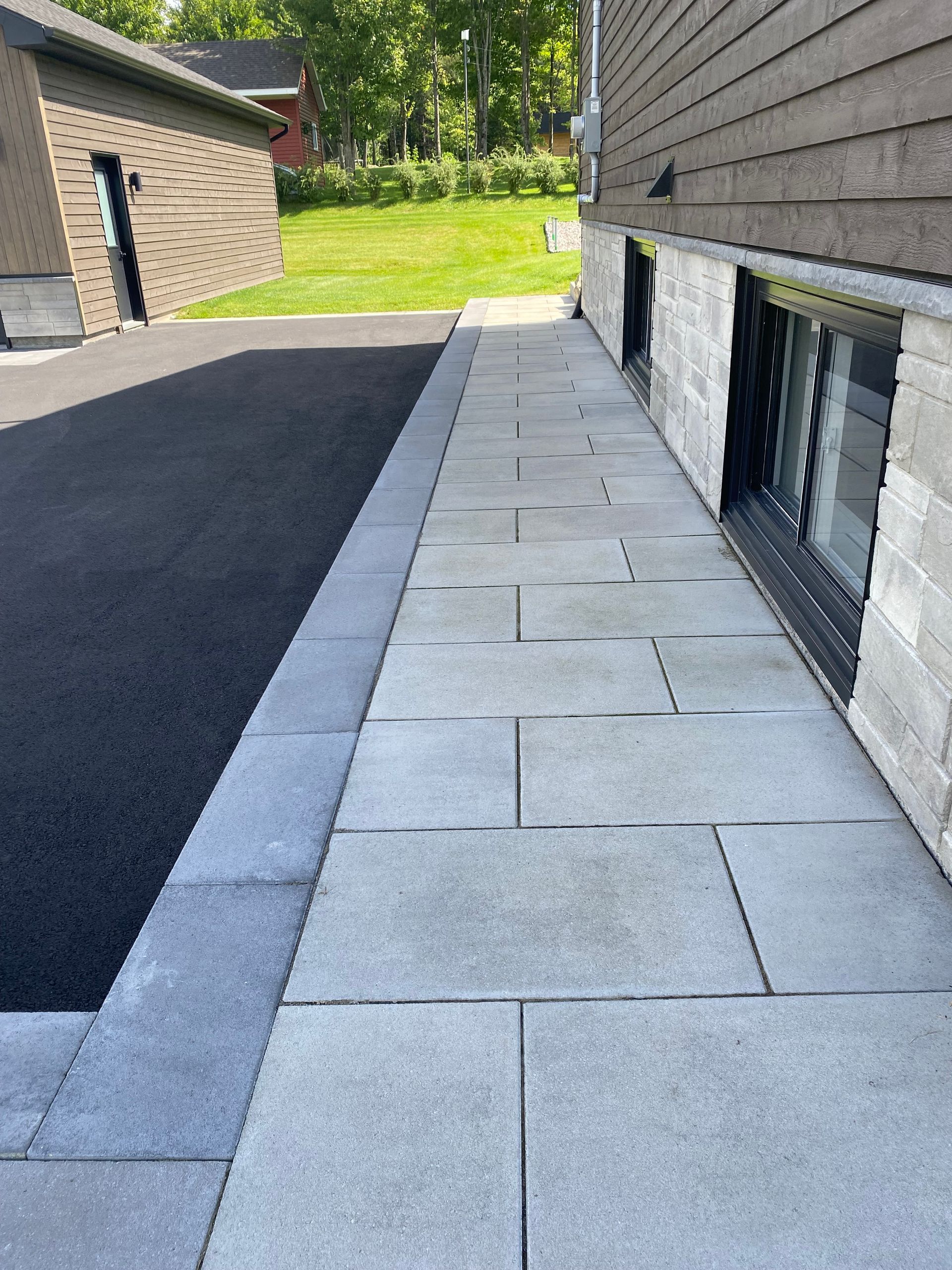 Un trottoir menant à une maison avec une fenêtre au sous-sol.