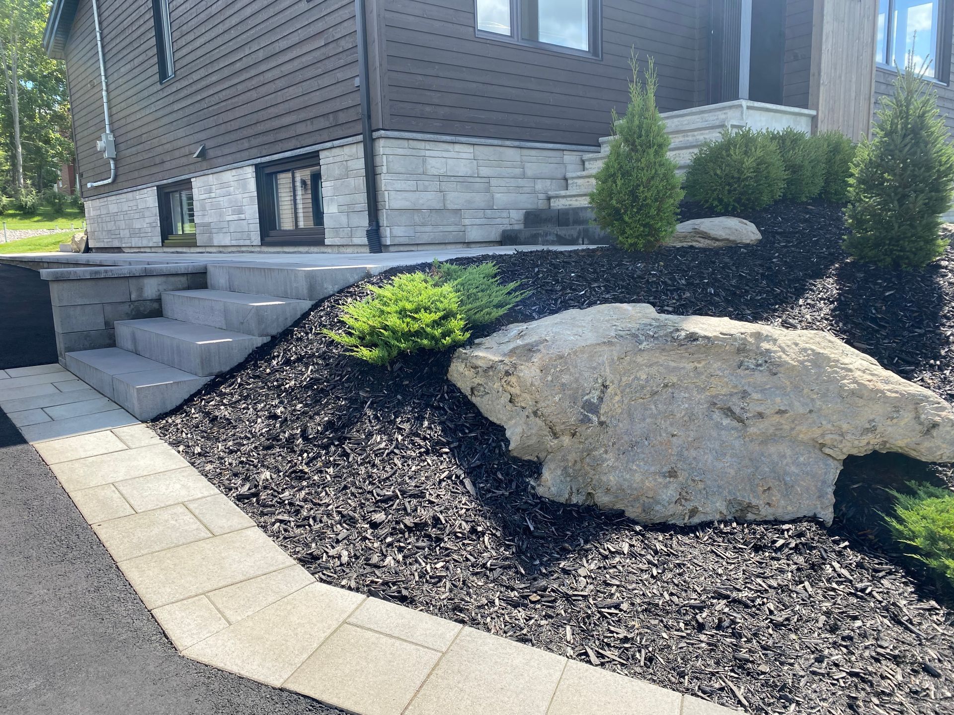 Une maison avec des escaliers et un gros rocher devant.