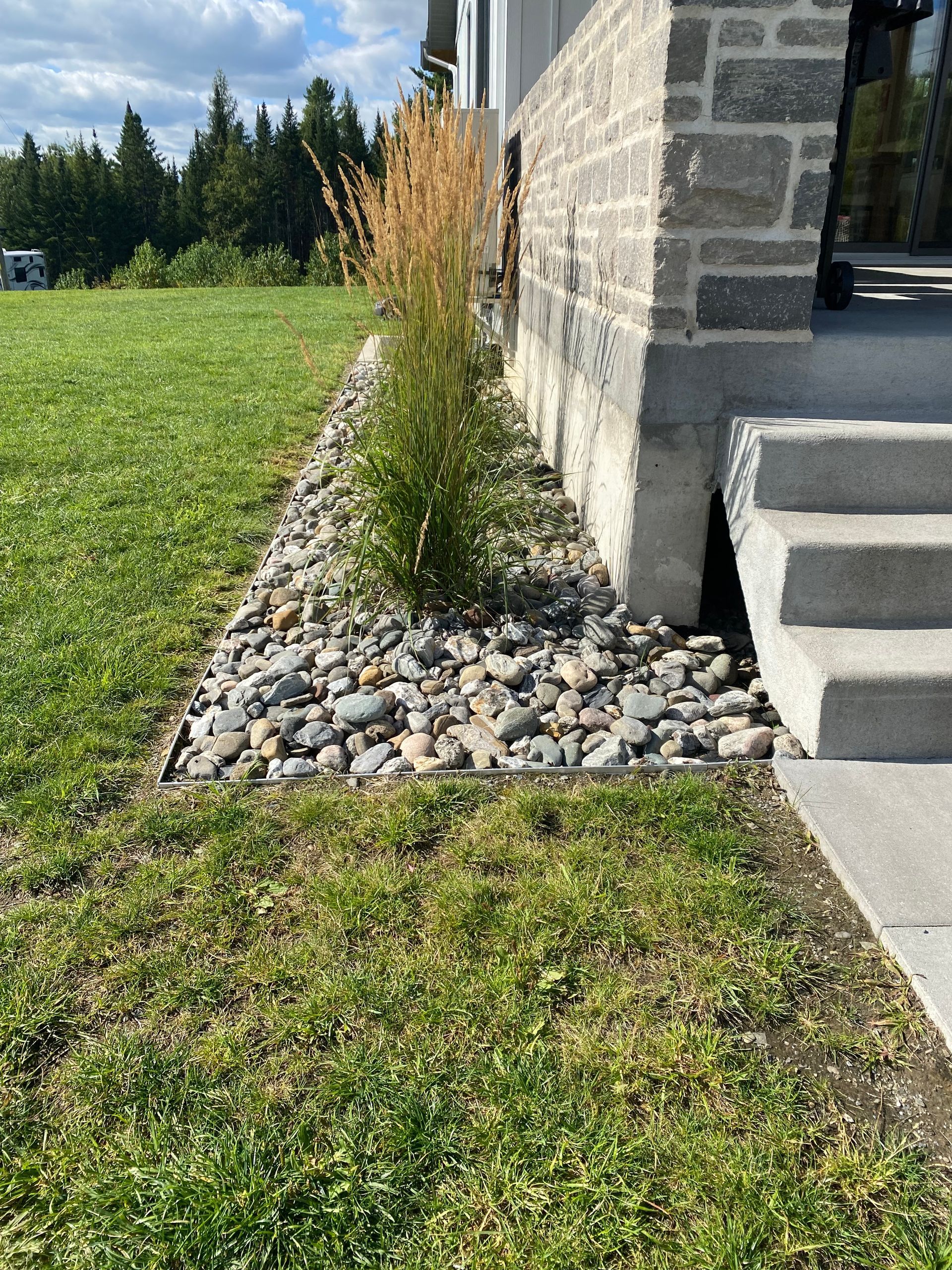 Une pelouse avec un mur de pierre et des escaliers devant.