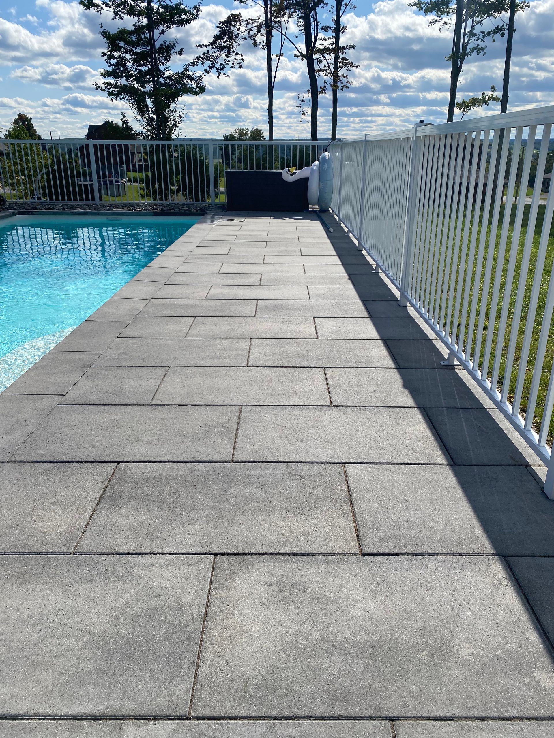 Une allée menant à une piscine avec une clôture blanche.