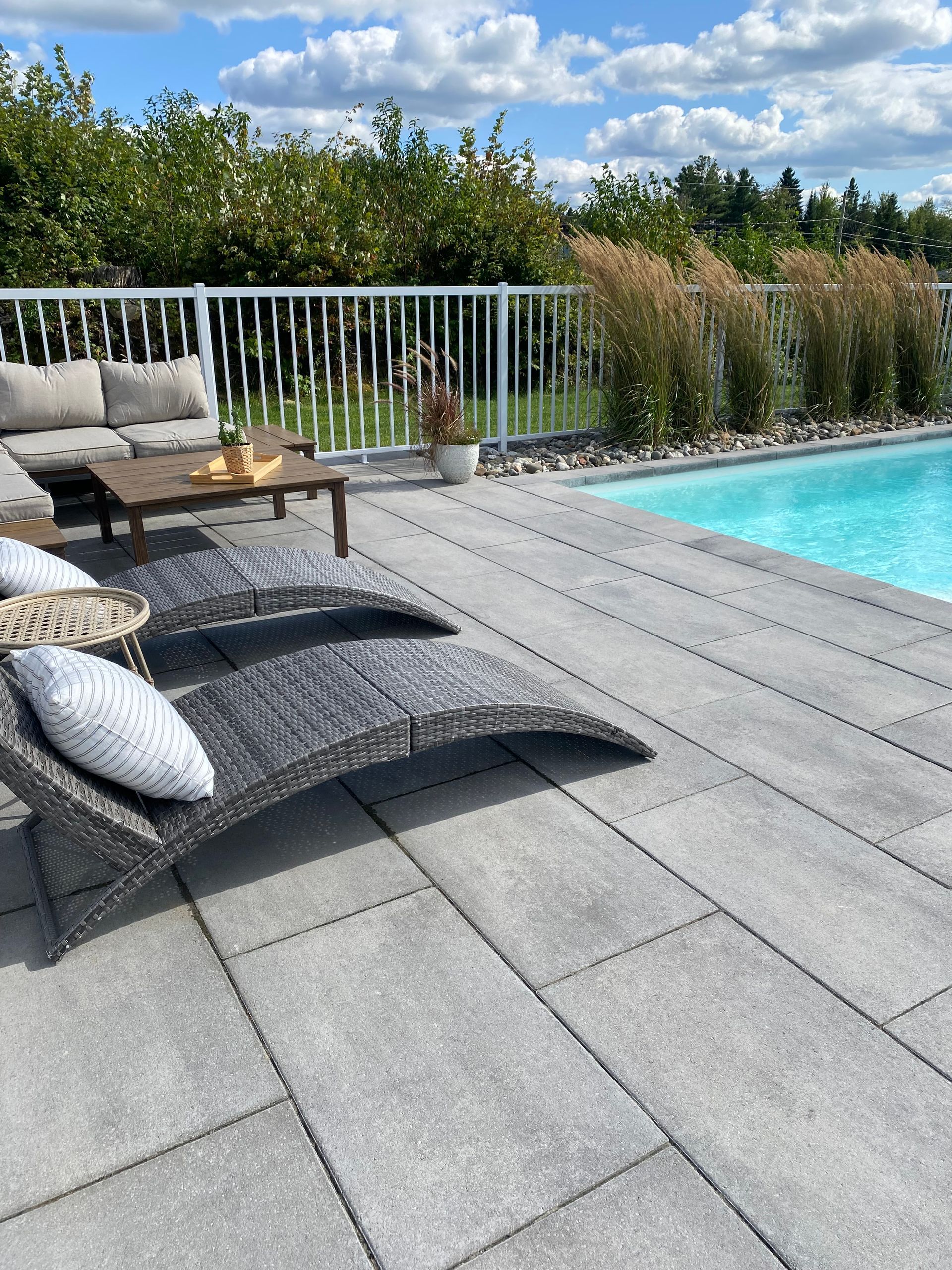 Un patio avec un canapé et des chaises à côté d'une piscine