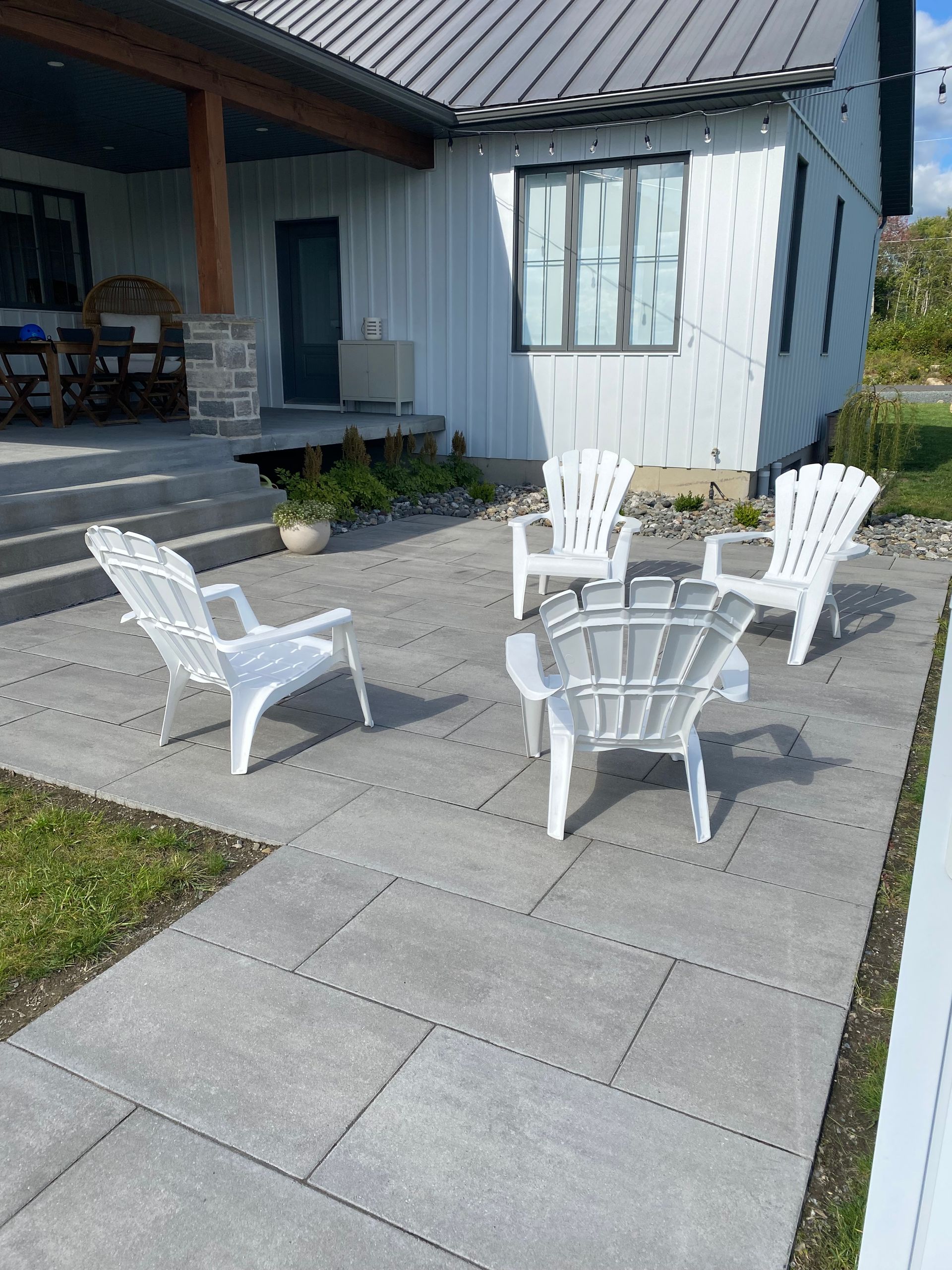 Un patio avec des chaises et un foyer devant une maison blanche.