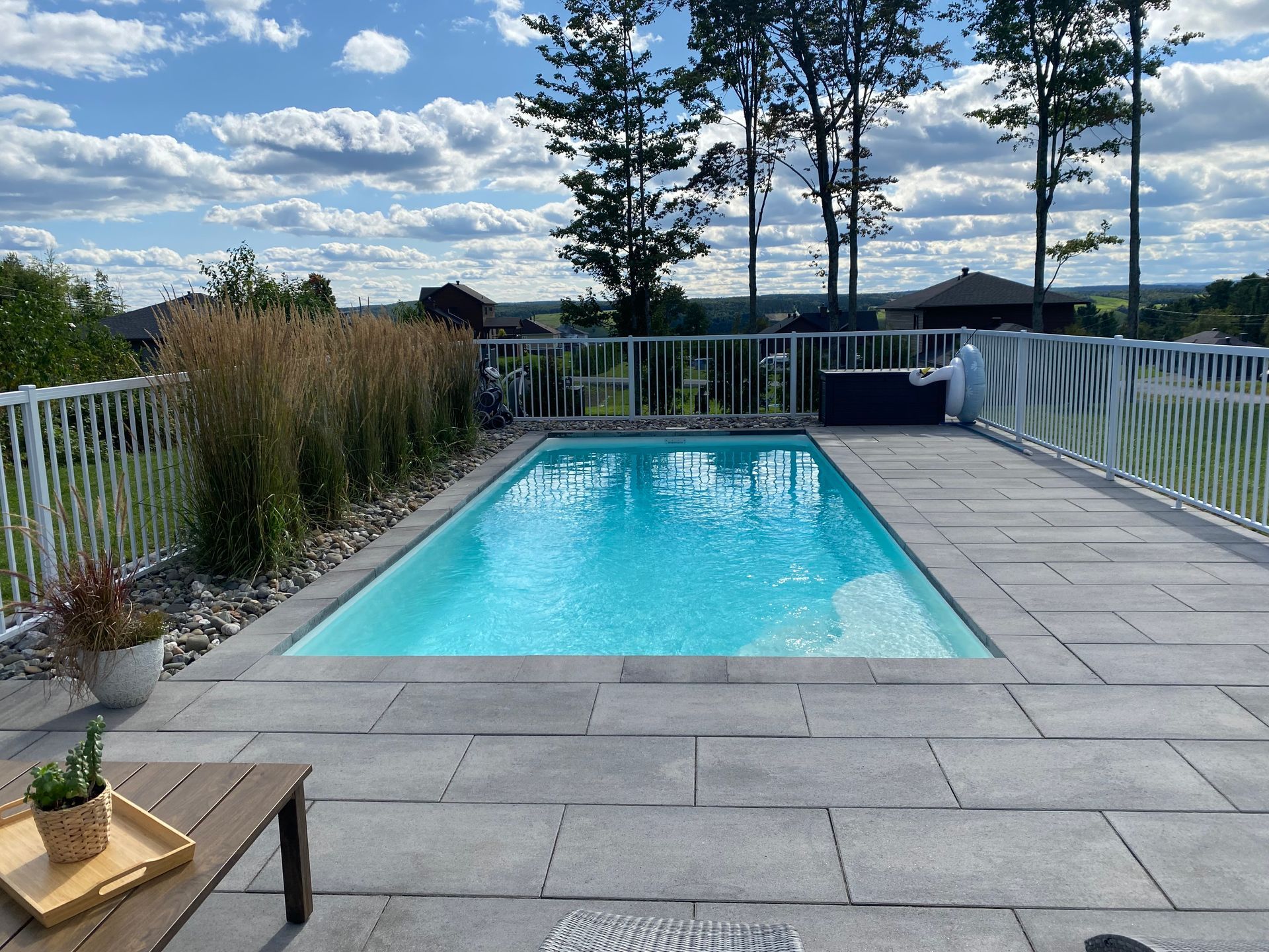 Une grande piscine est entourée d'une clôture et d'un patio.