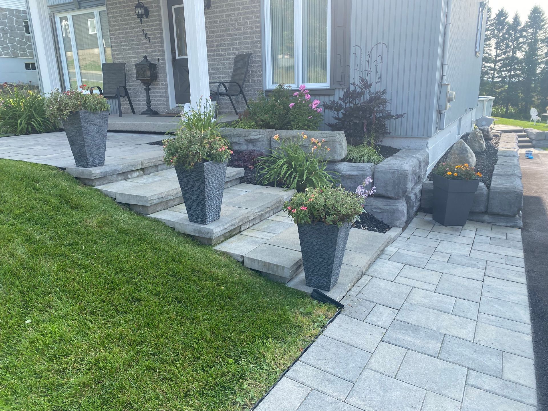Une allée en pierre menant à une maison avec des plantes en pot dessus.
