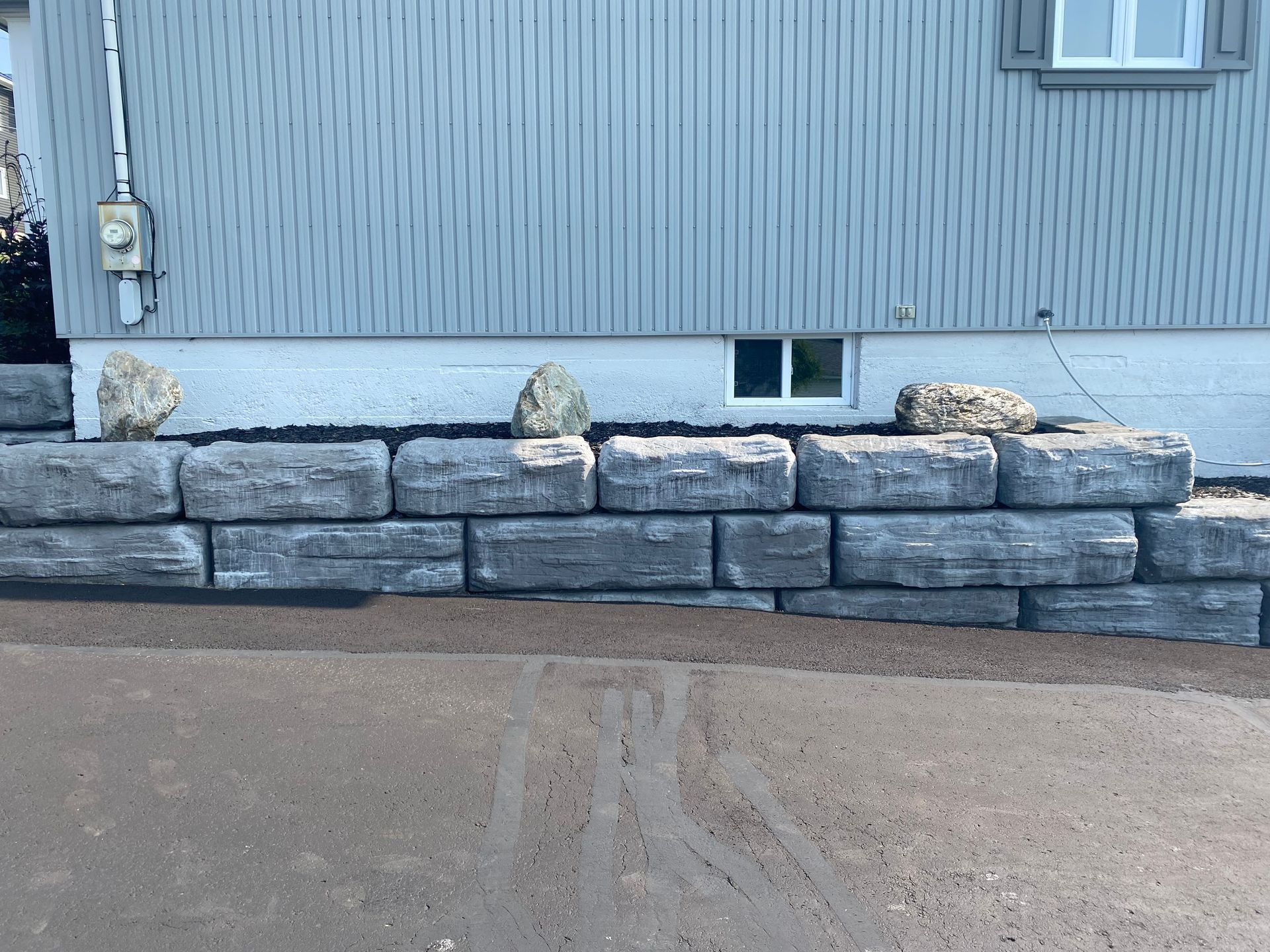 Un mur de pierre est en train d'être construit devant une maison.