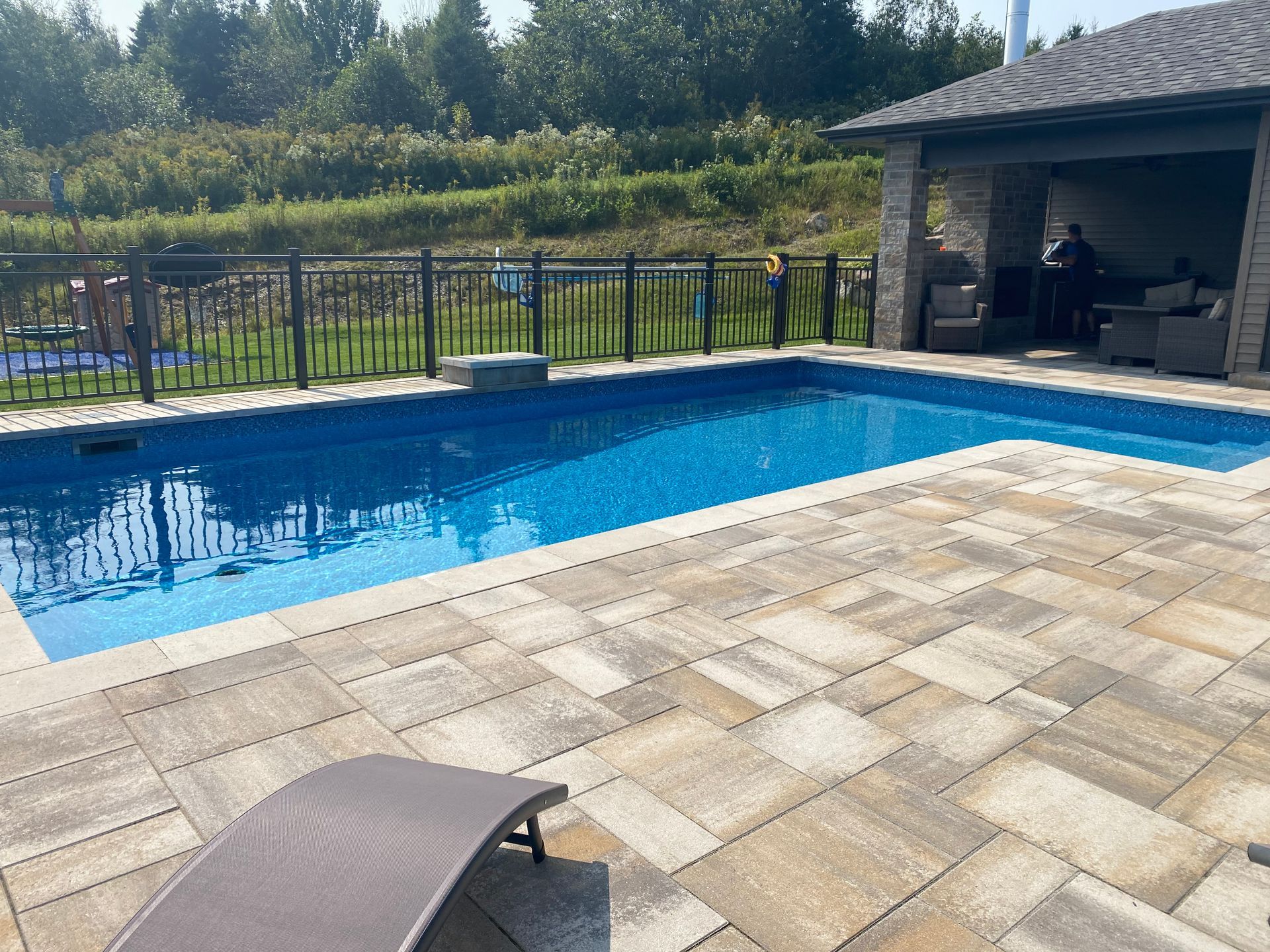 Une grande piscine est entourée d'un patio et d'une clôture.