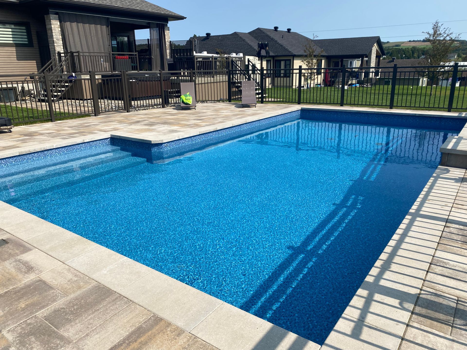 Une grande piscine dans une cour arrière avec une maison en arrière-plan.