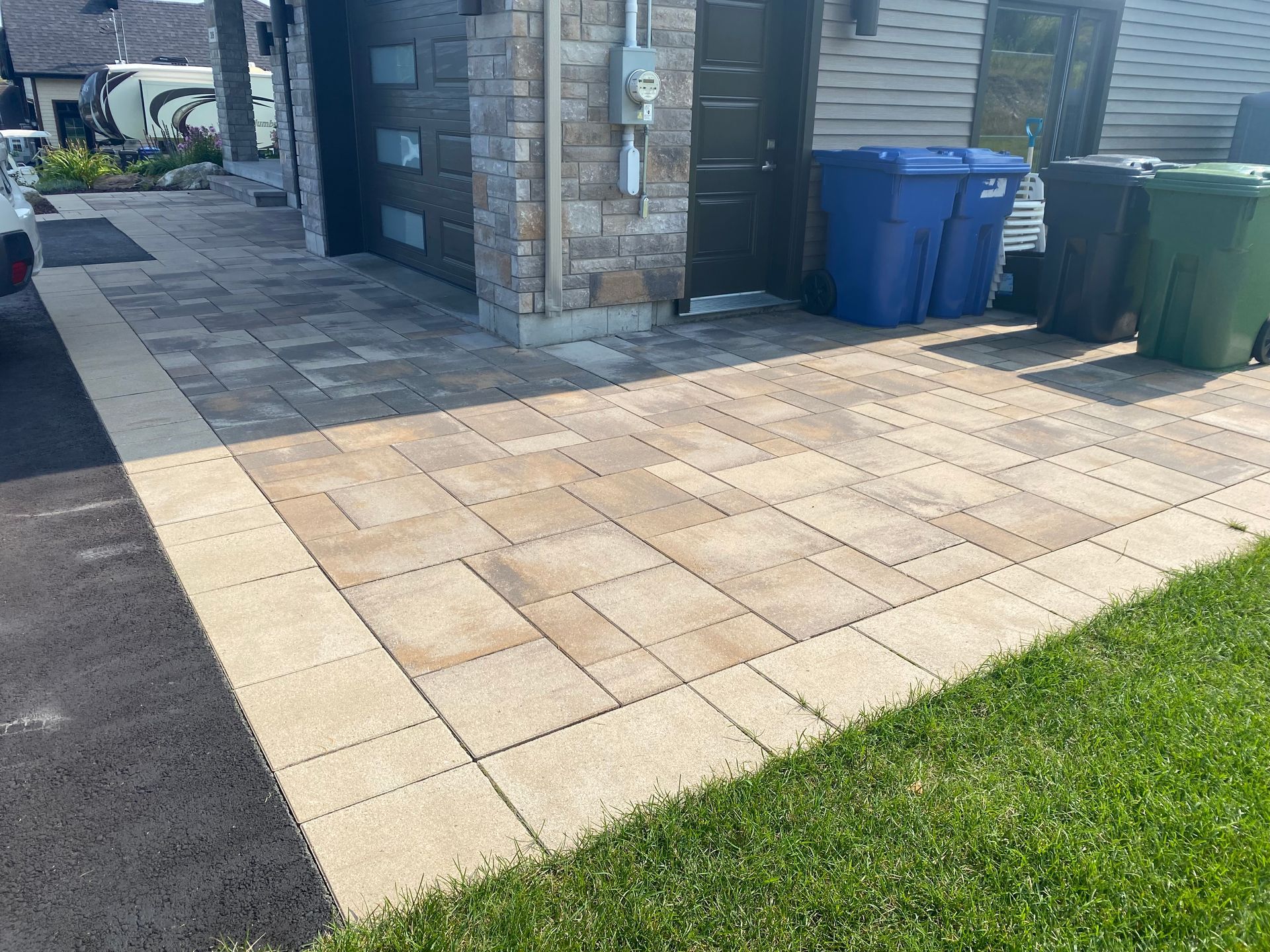 Une allée en briques avec des poubelles devant une maison.