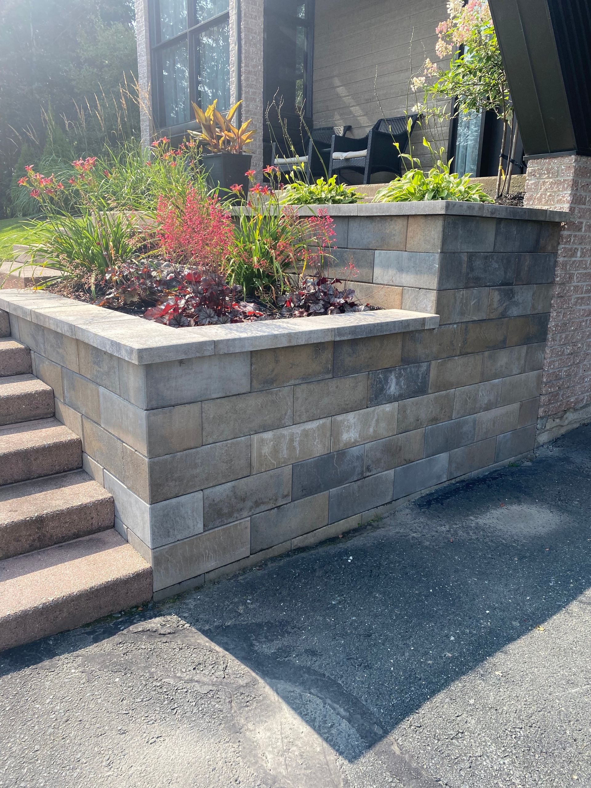 Un mur de briques avec des escaliers et des plantes devant une maison.