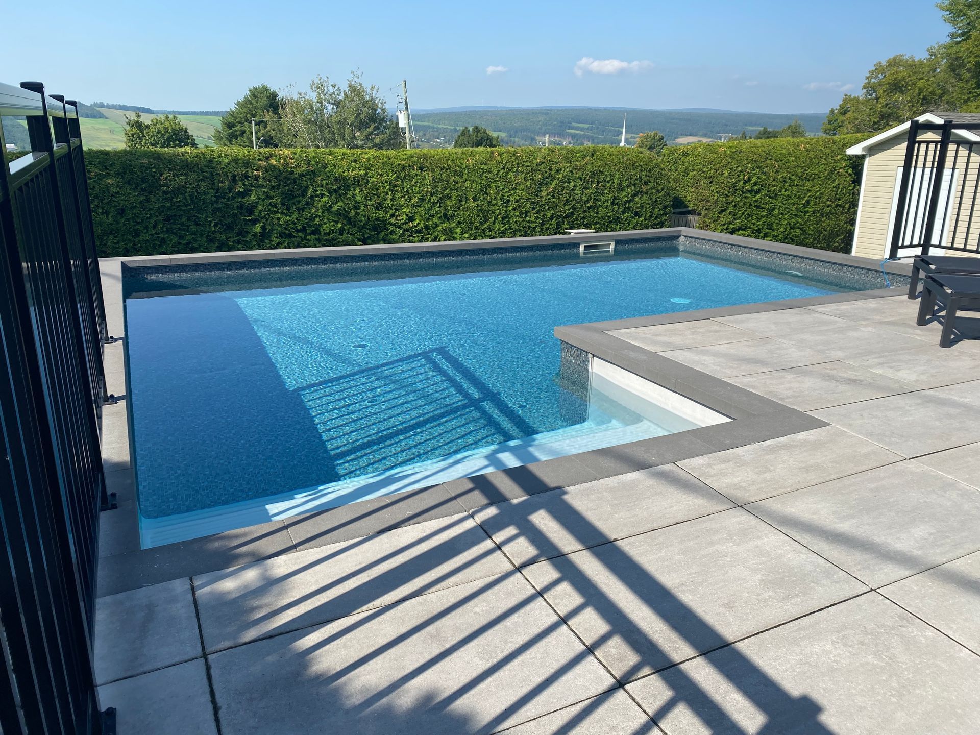 Une grande piscine est entourée d'une clôture et d'un patio.