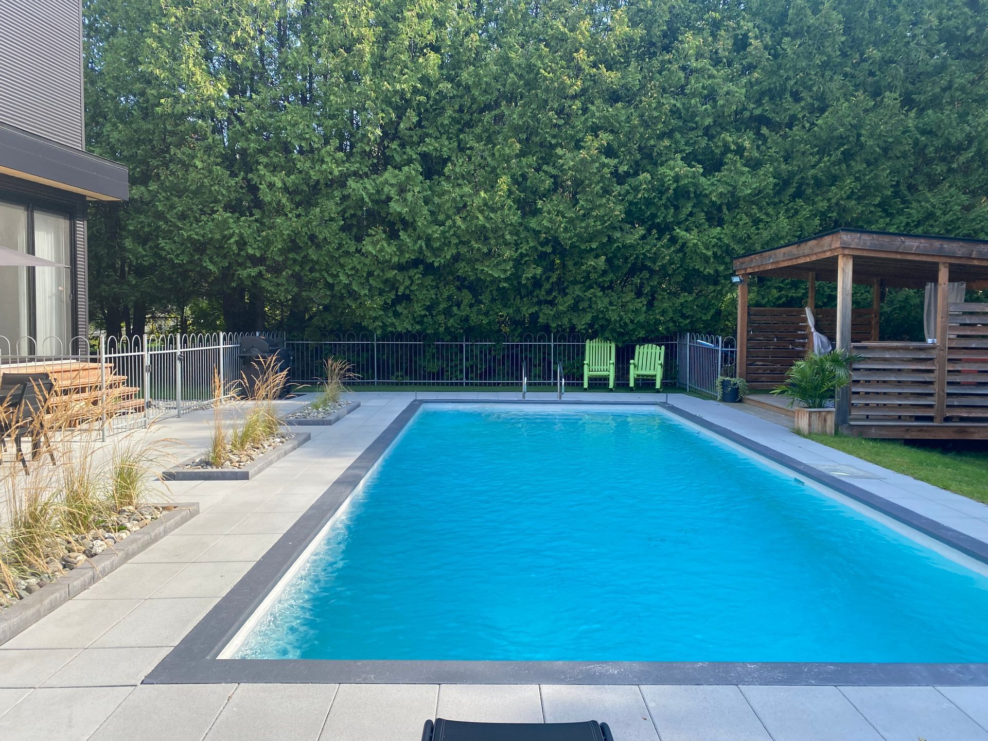 Une grande piscine entourée d'arbres et de chaises