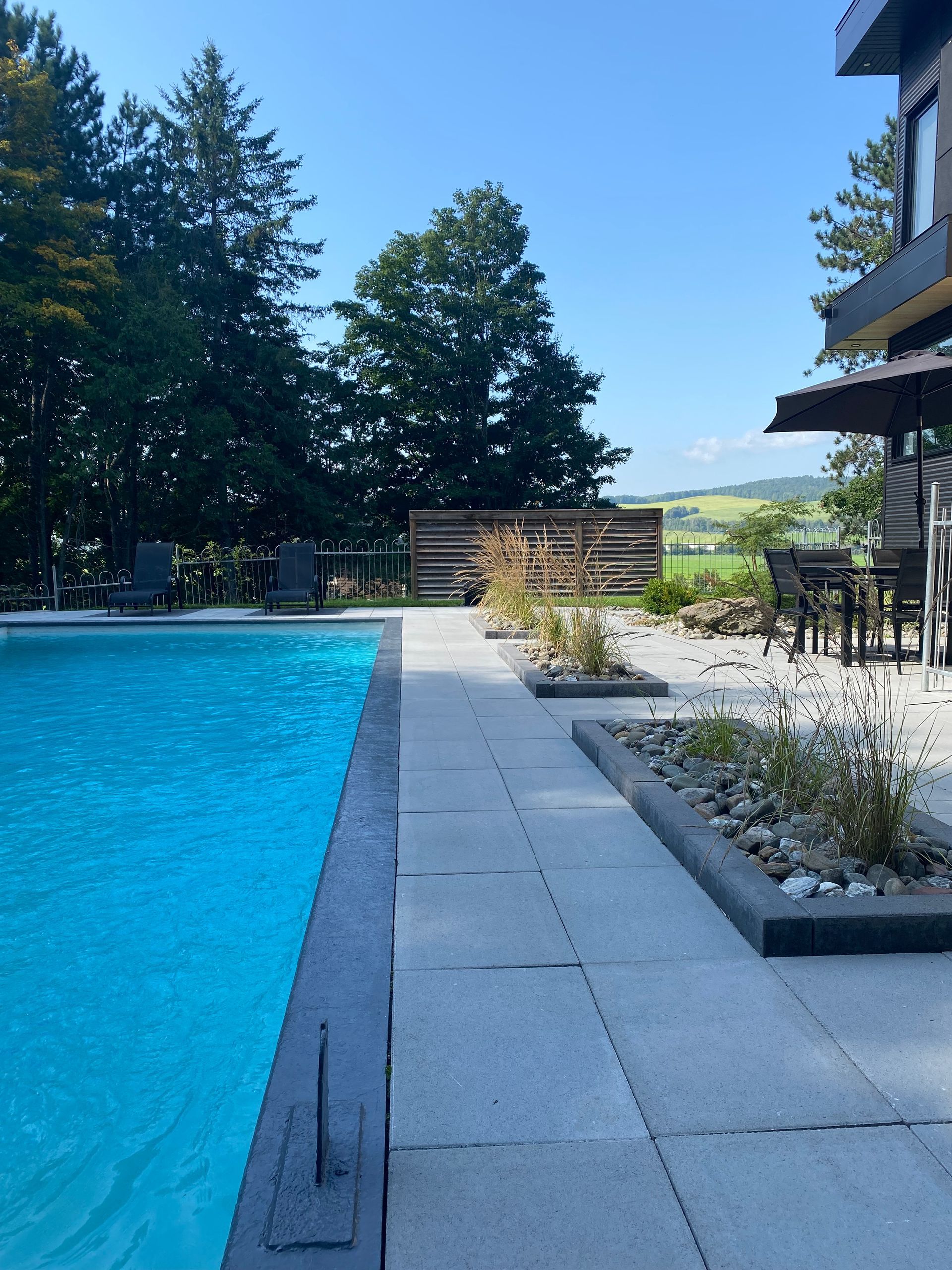 Une grande piscine est entourée d'un patio avec chaises et parasols