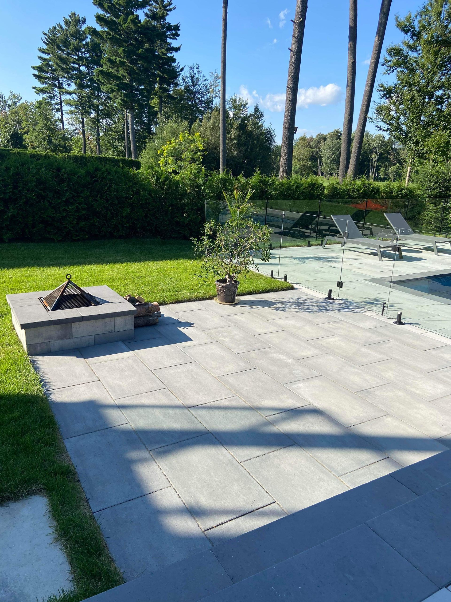 Un patio avec un foyer et une piscine en arrière-plan