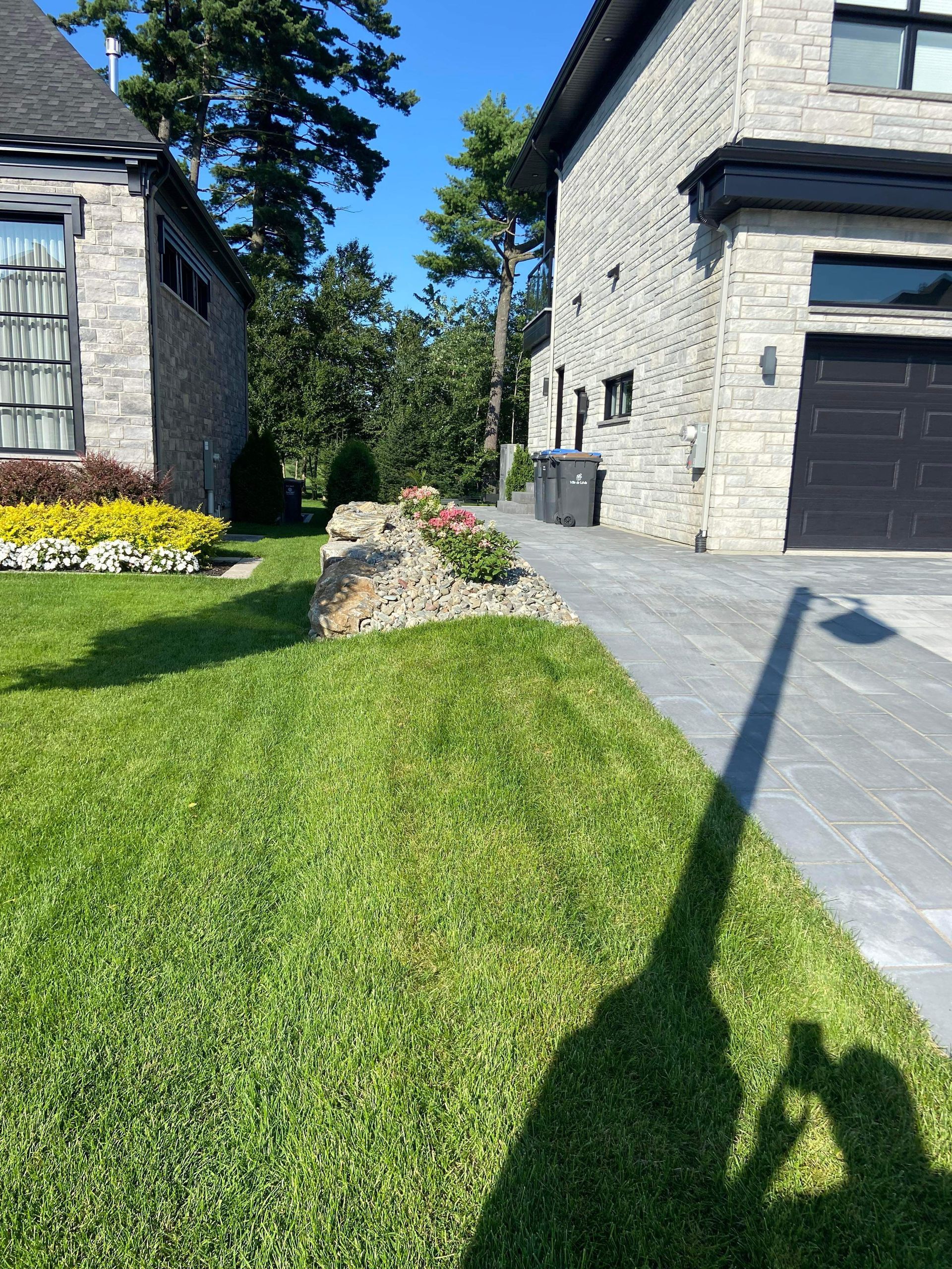 L'ombre d'une personne est projetée sur l'herbe devant une maison.