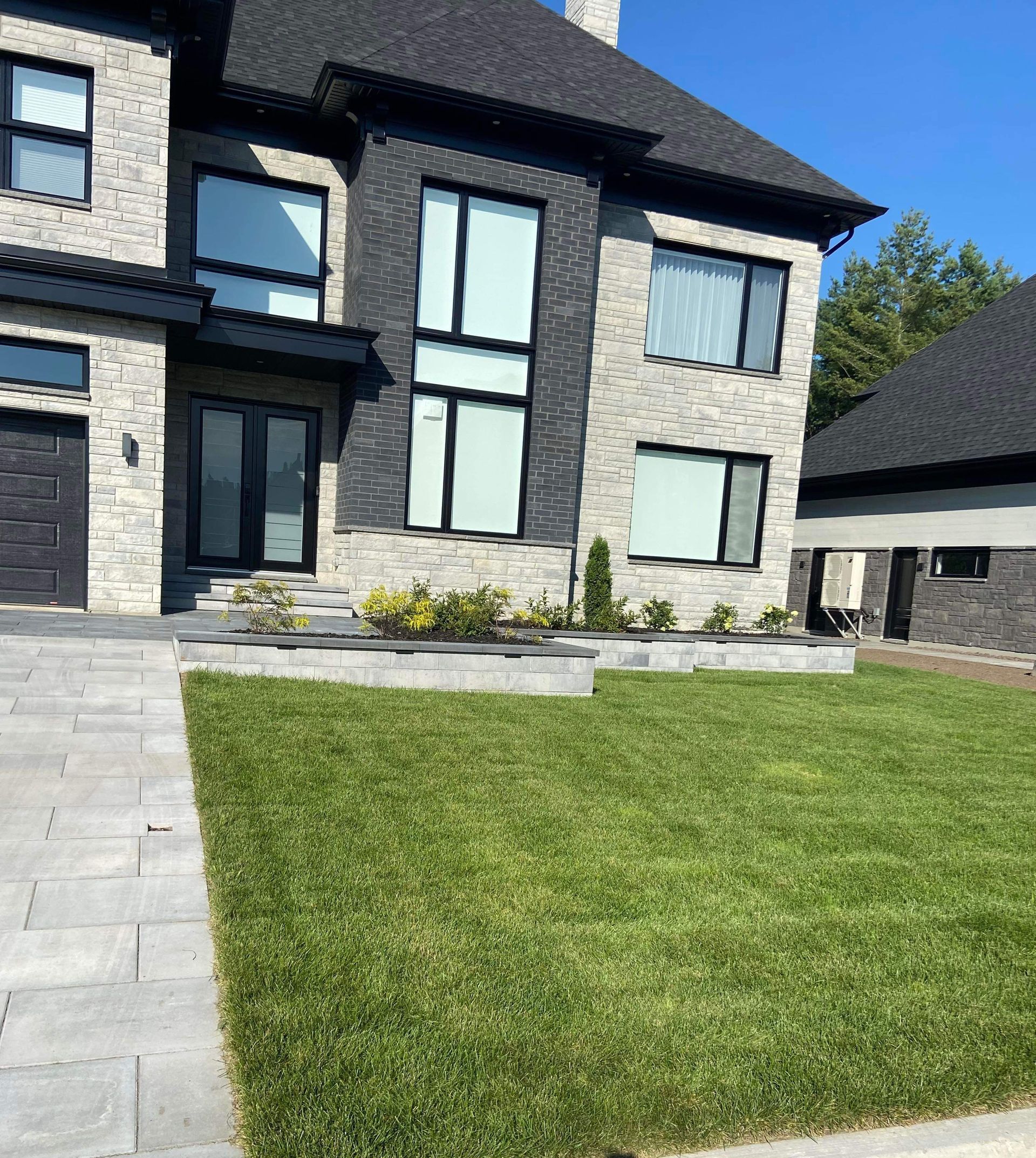 Une grande maison en briques avec une pelouse verte luxuriante devant elle.