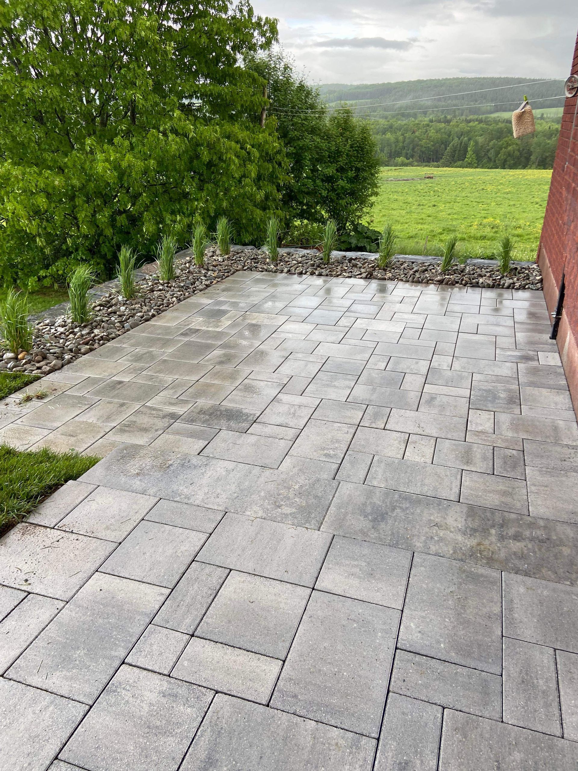Une terrasse avec vue sur un champ et des arbres par temps nuageux.