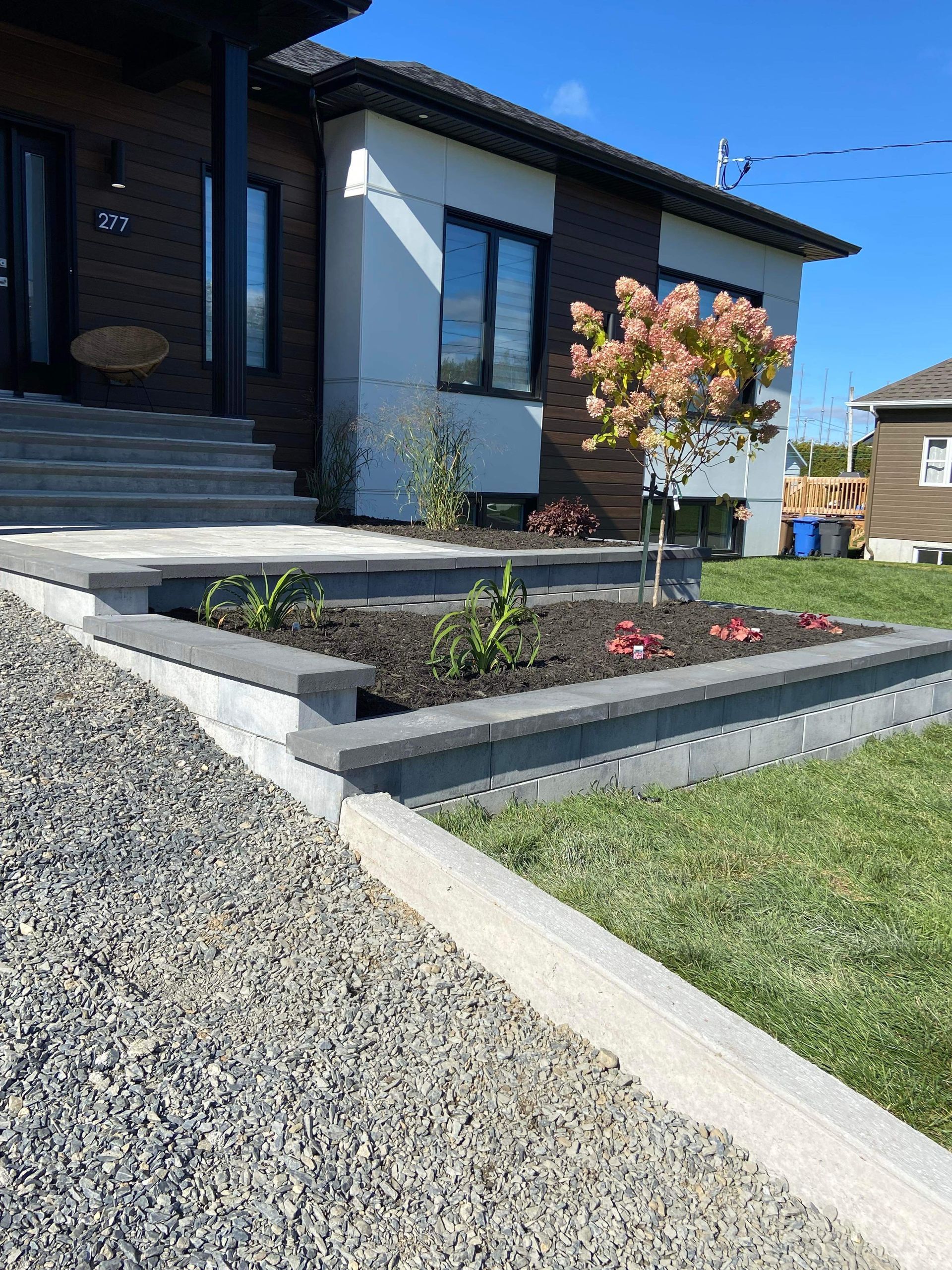 Une maison avec des escaliers et une jardinière devant.