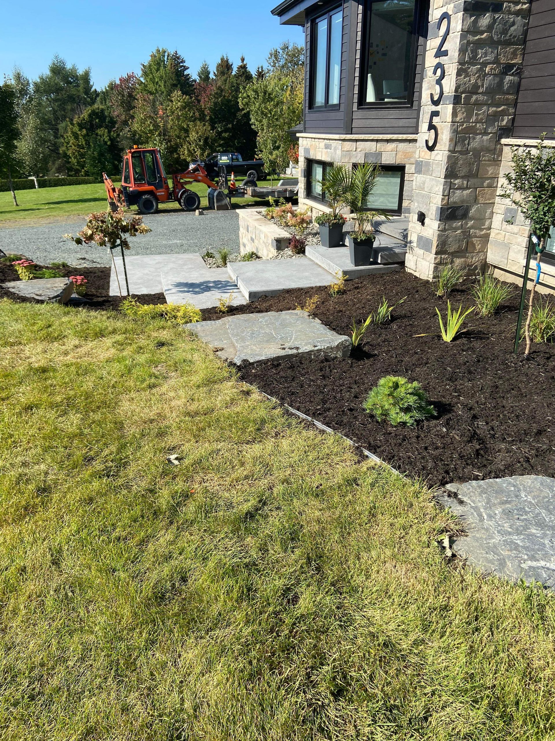 Une grande pelouse devant une maison avec un chariot élévateur garé dans l'allée.