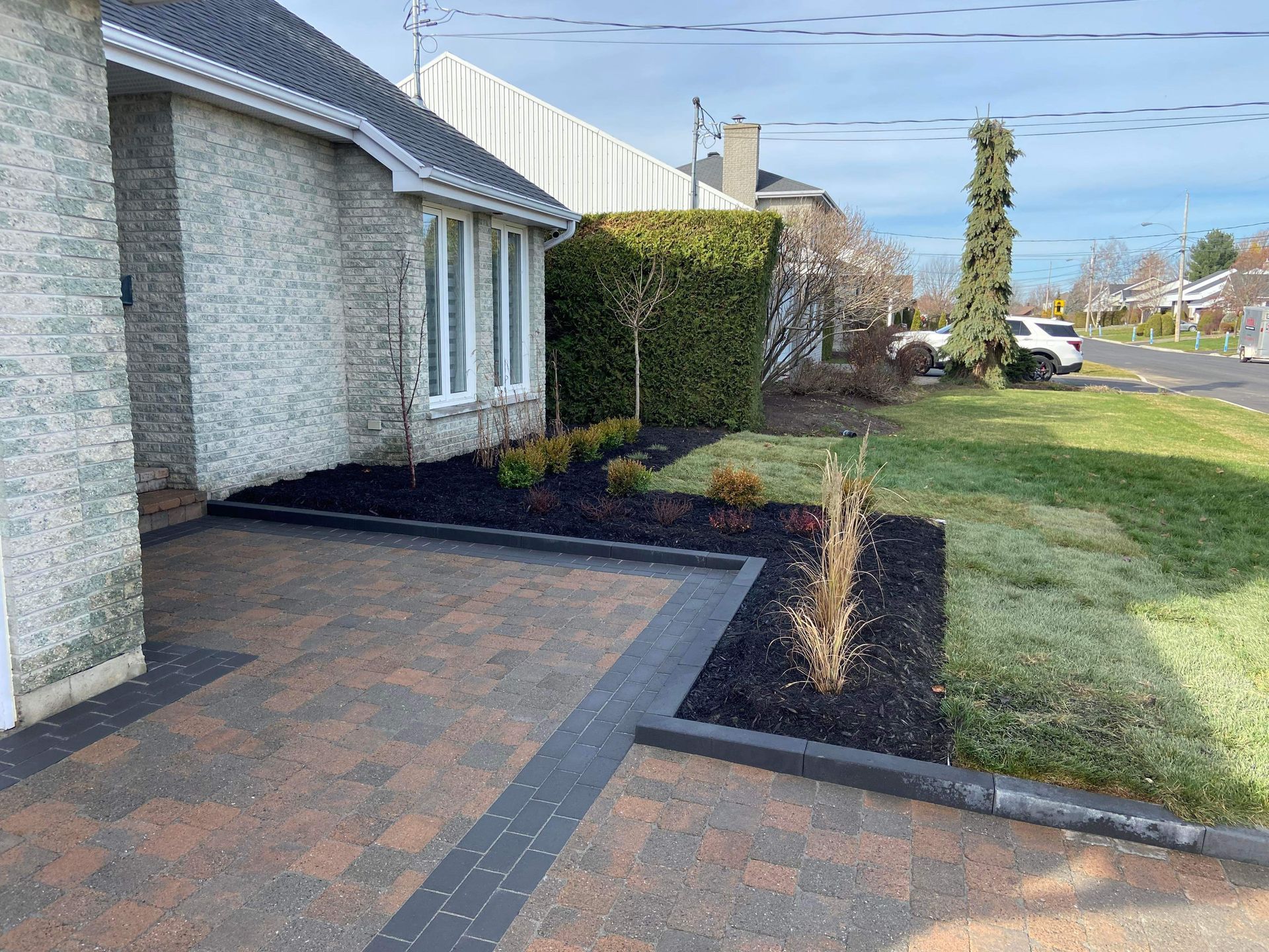 Une maison en brique avec une allée et une pelouse devant.