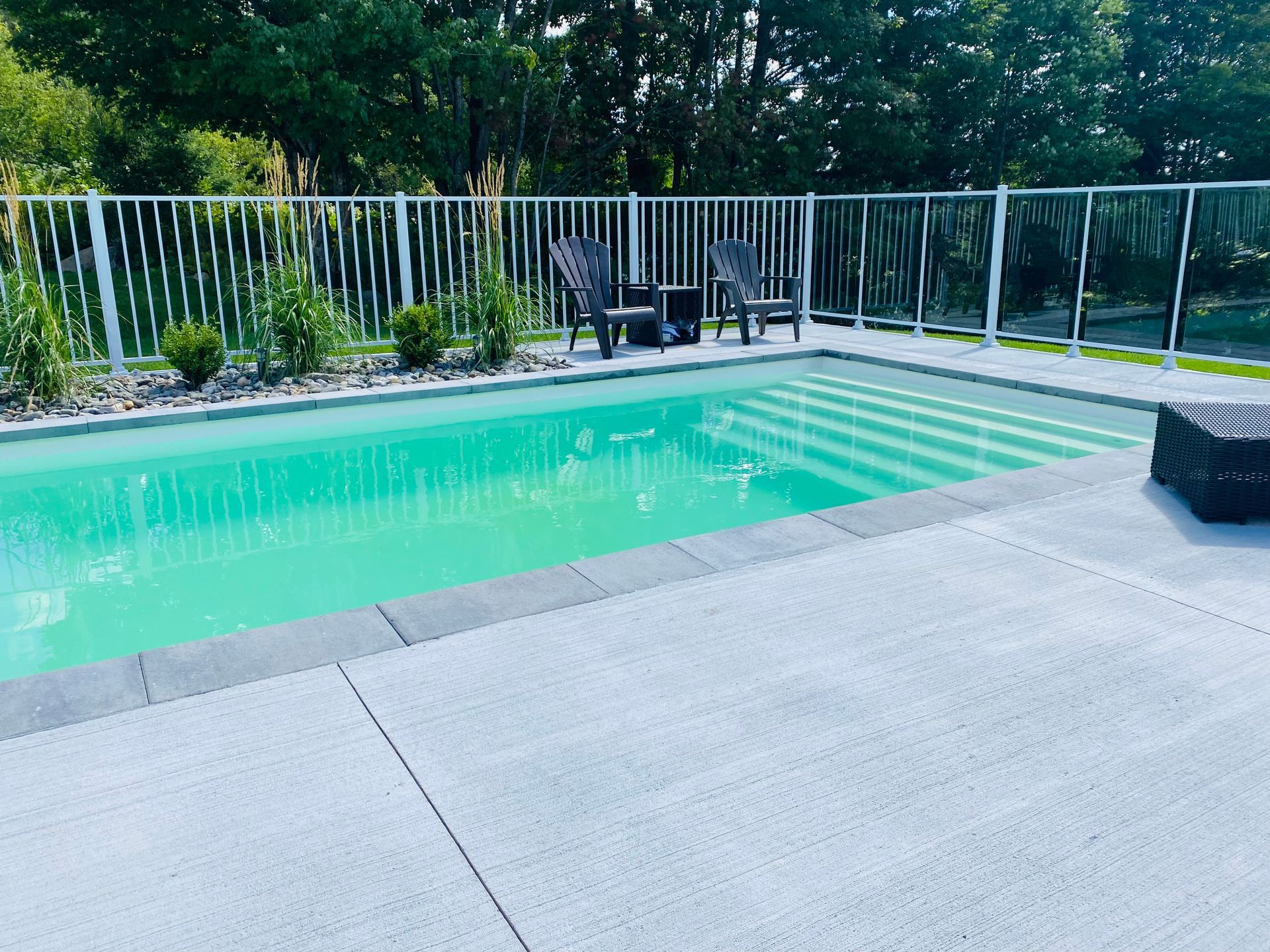 Une grande piscine avec des chaises et une clôture autour