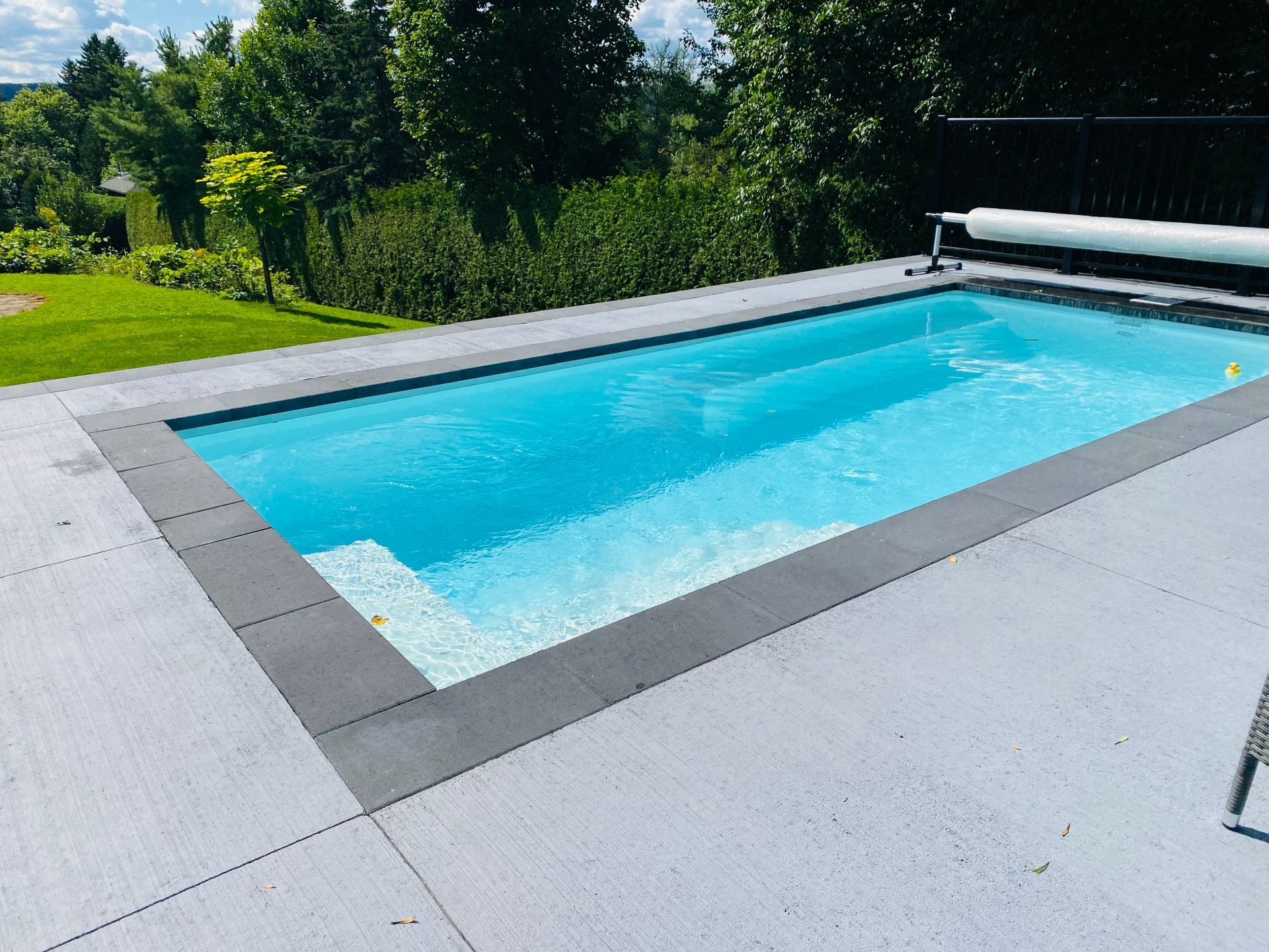 Une grande piscine est posée sur un patio en béton.