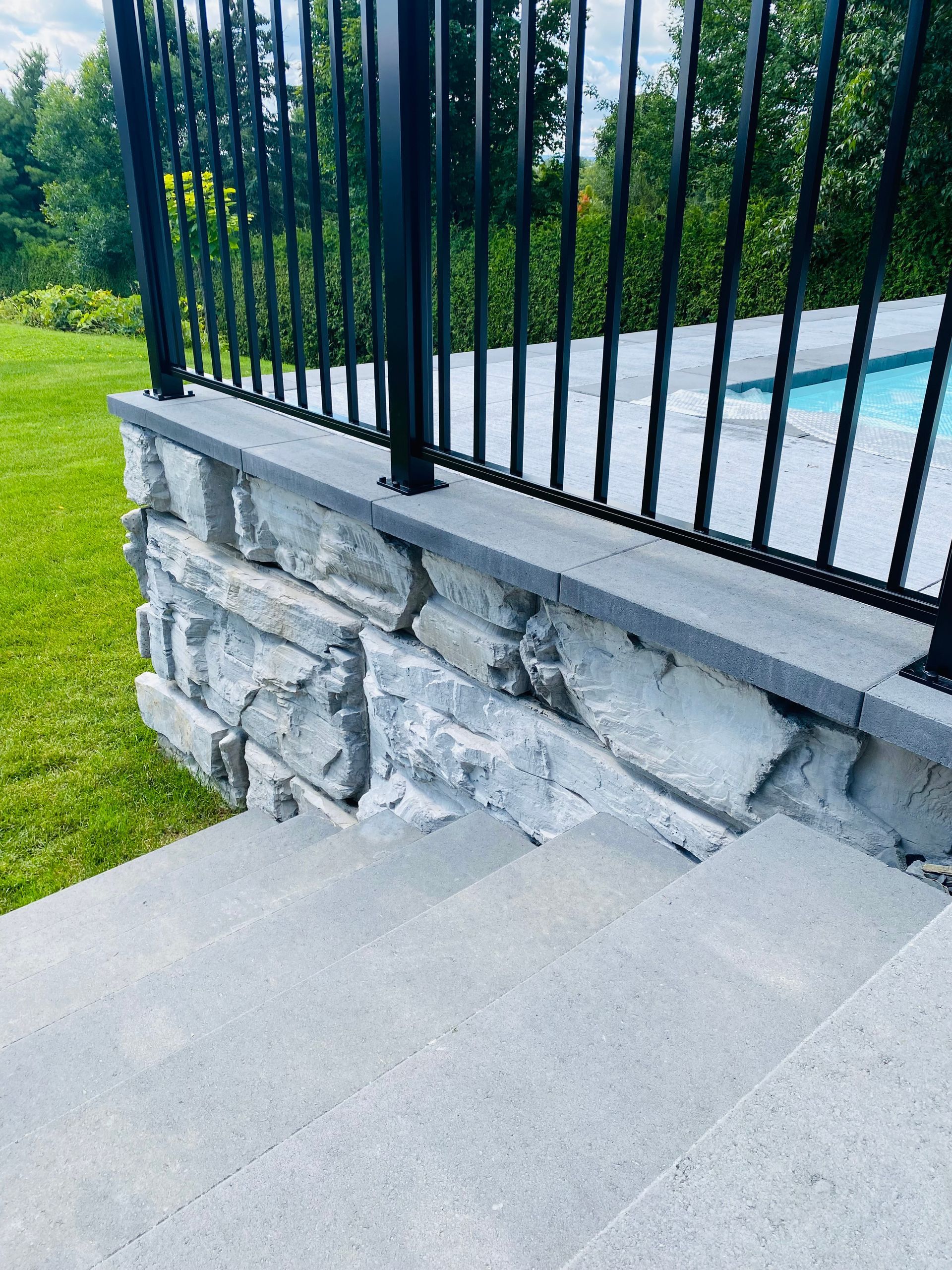 Un mur de pierre avec des escaliers menant à une piscine.