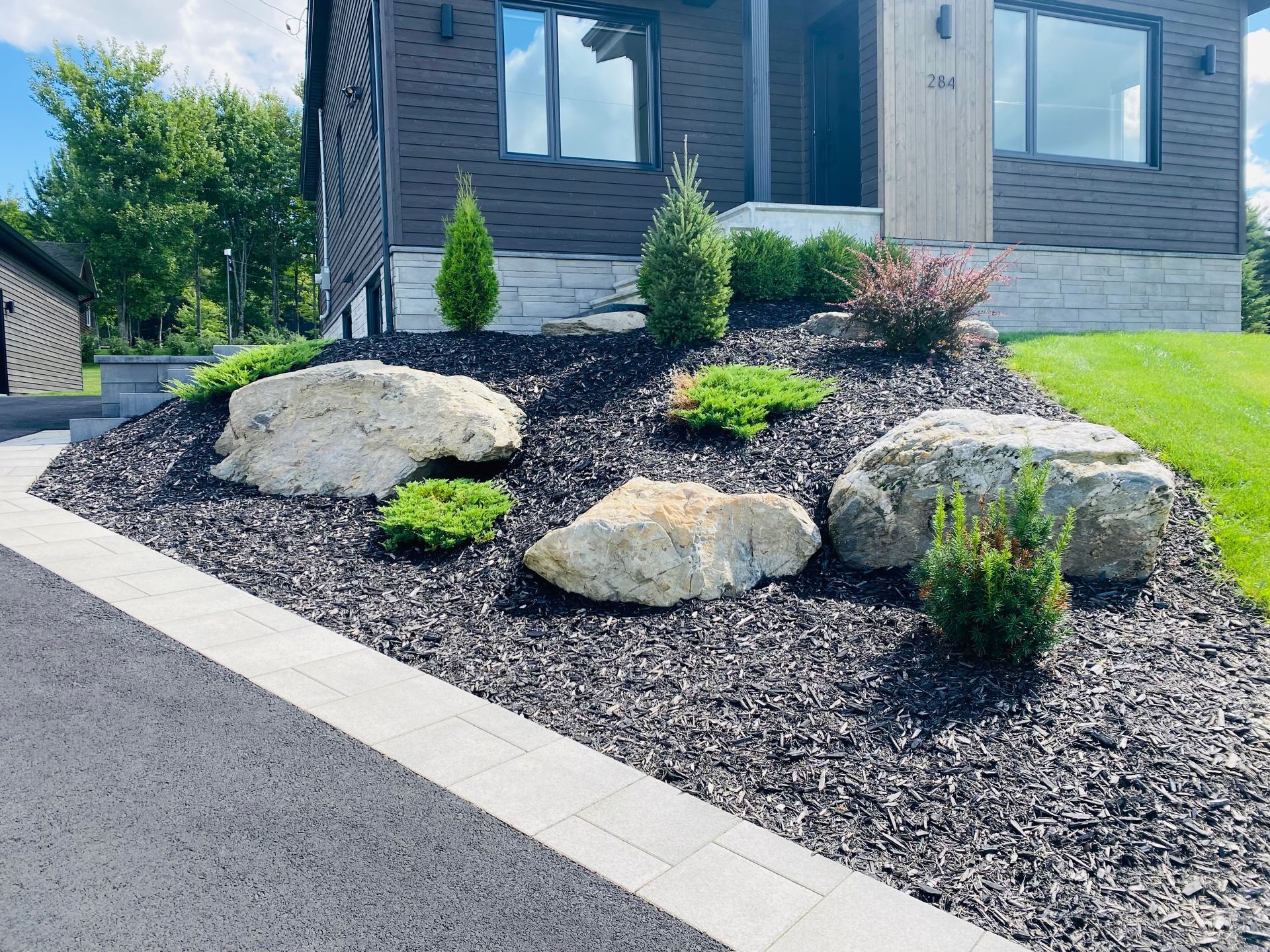 Un jardin avec des rochers et des plantes devant une maison.