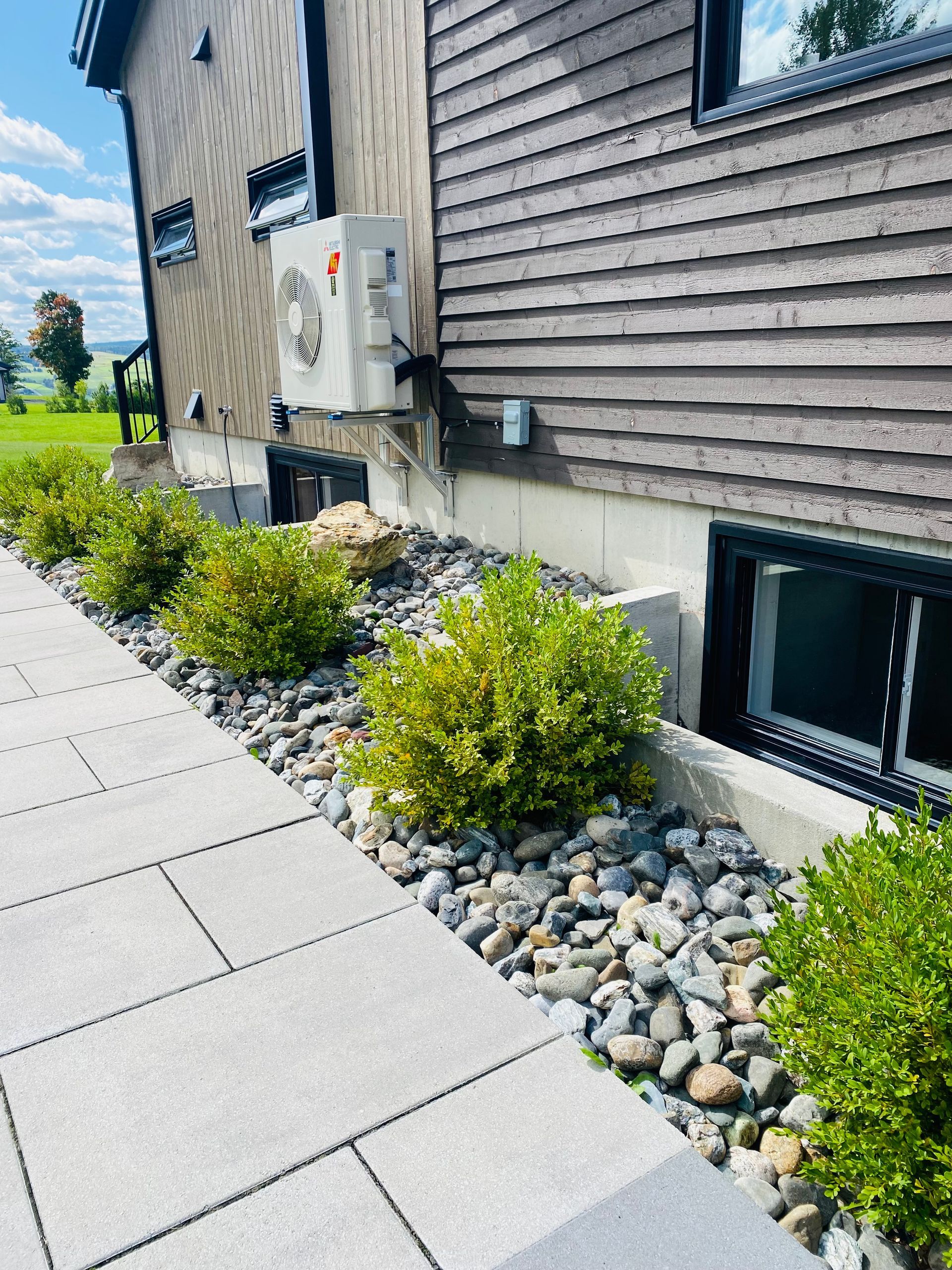 Une allée menant à une maison avec beaucoup de plantes et de rochers.