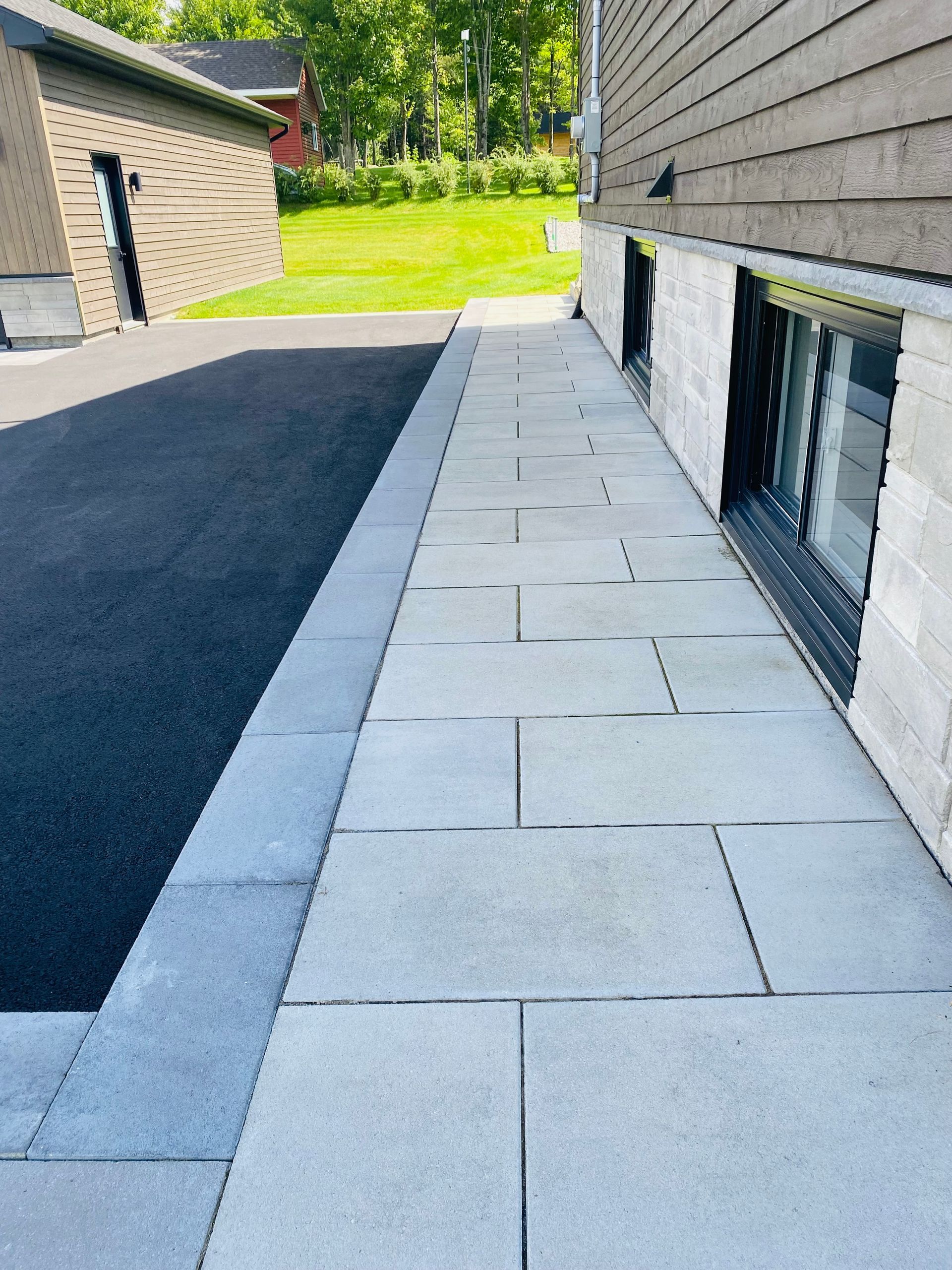 Un trottoir menant à une maison avec une fenêtre au sous-sol