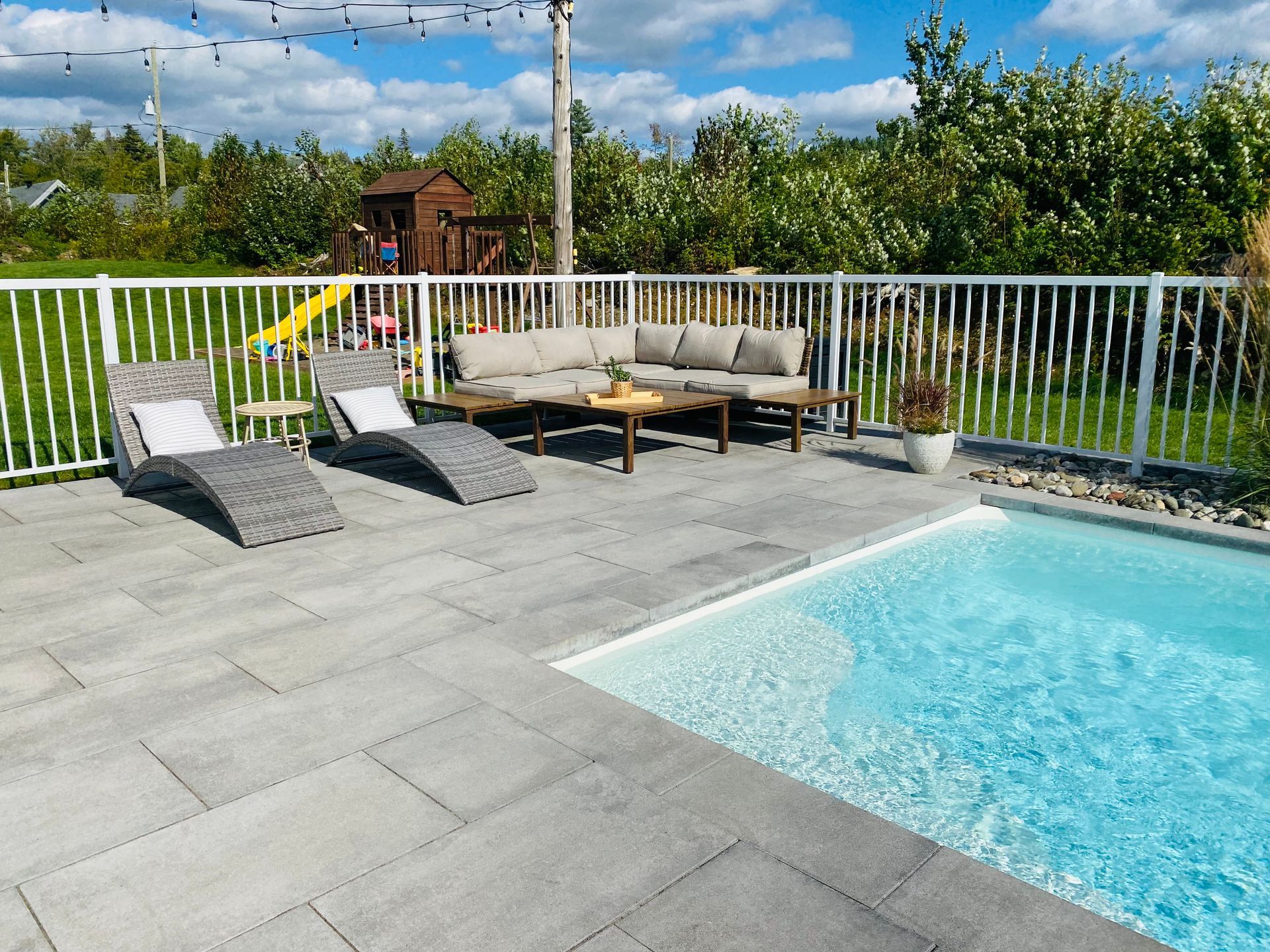 Un patio avec un canapé et des chaises à côté d'une piscine