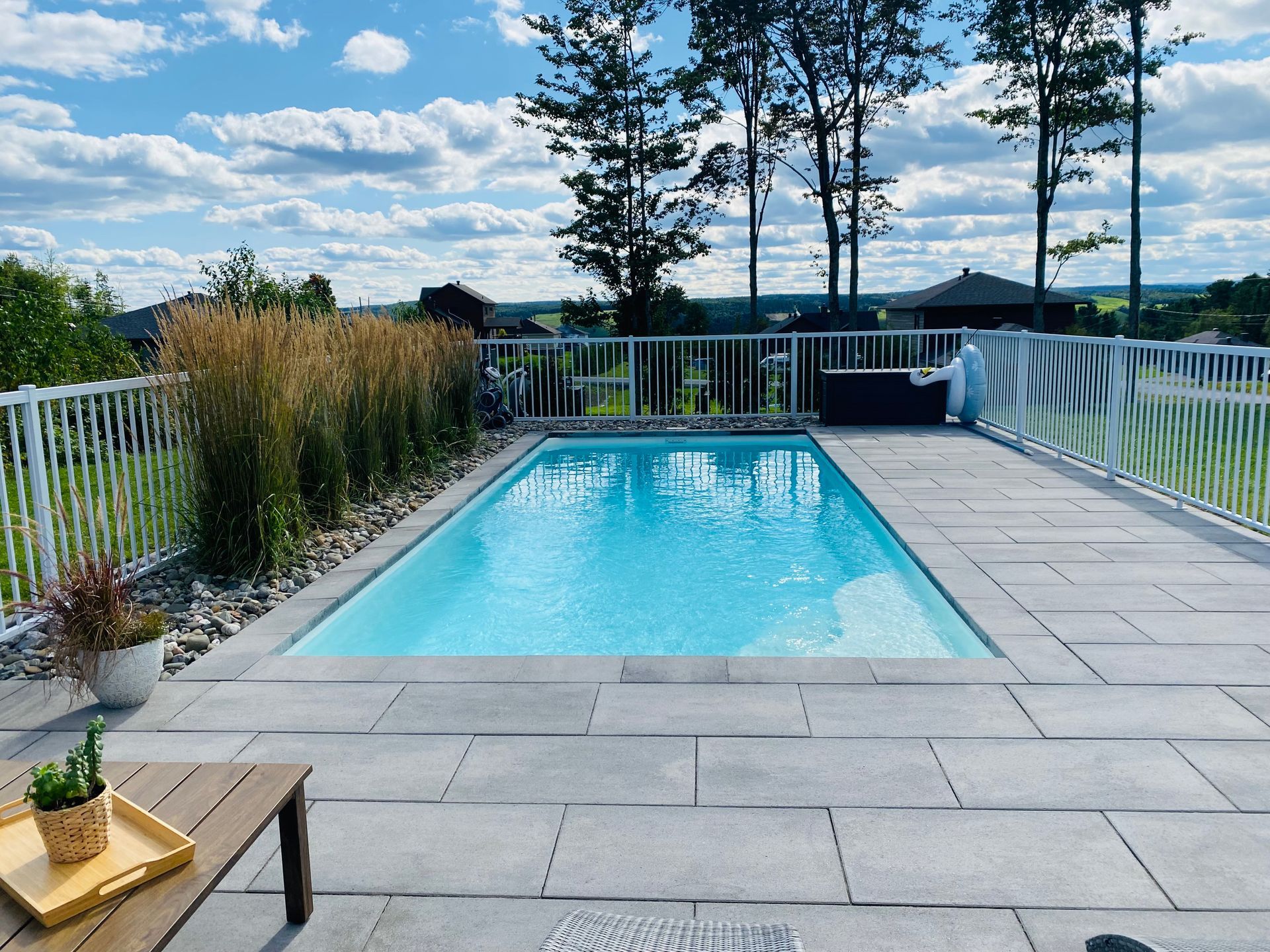 Une grande piscine est entourée d'une clôture et d'arbres
