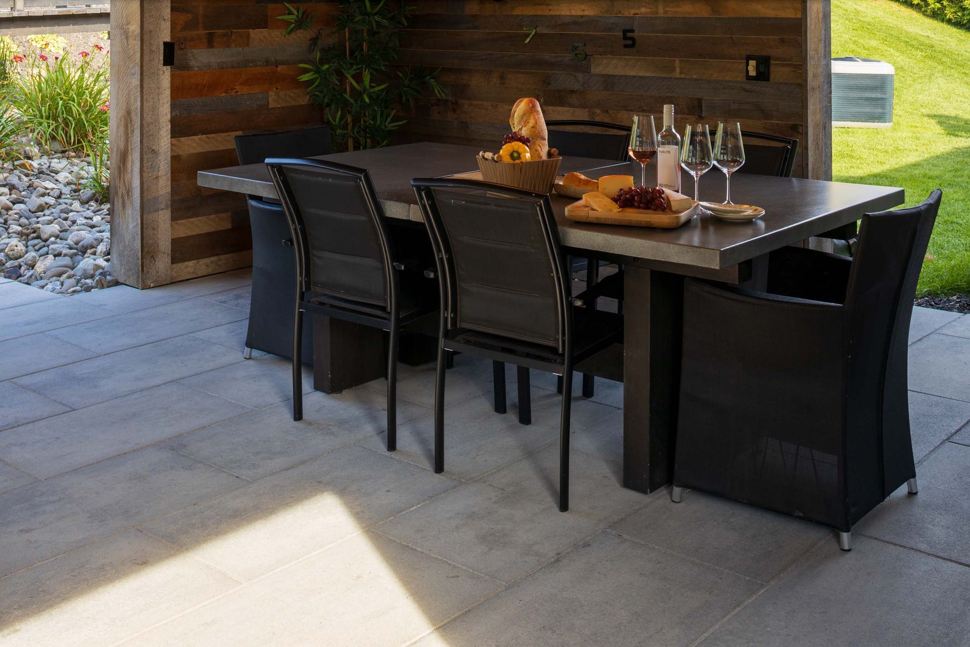 Un patio avec une table et des chaises et une bouteille de vin dessus