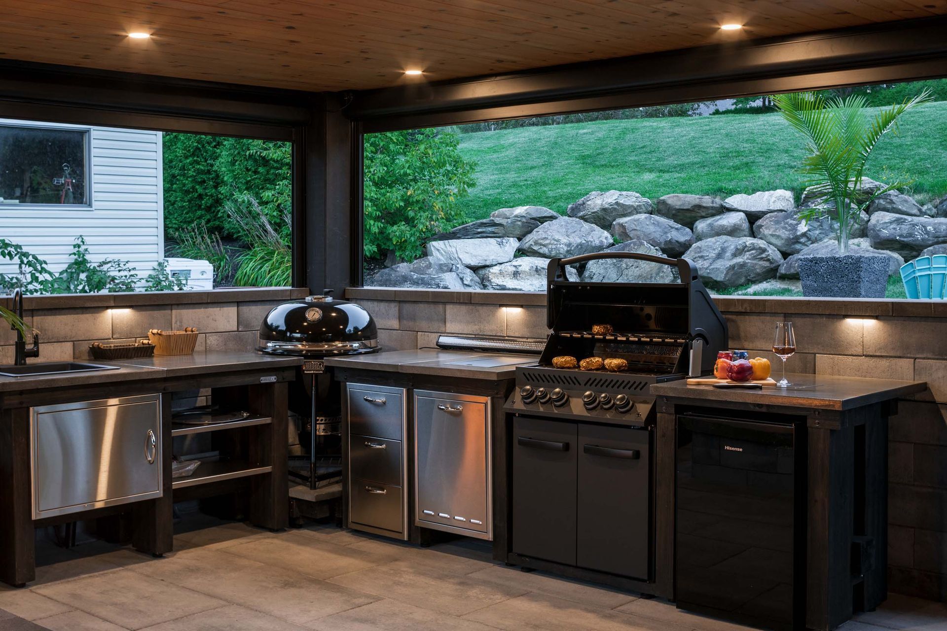 Une cuisine extérieure avec des appareils en acier inoxydable et un grill.