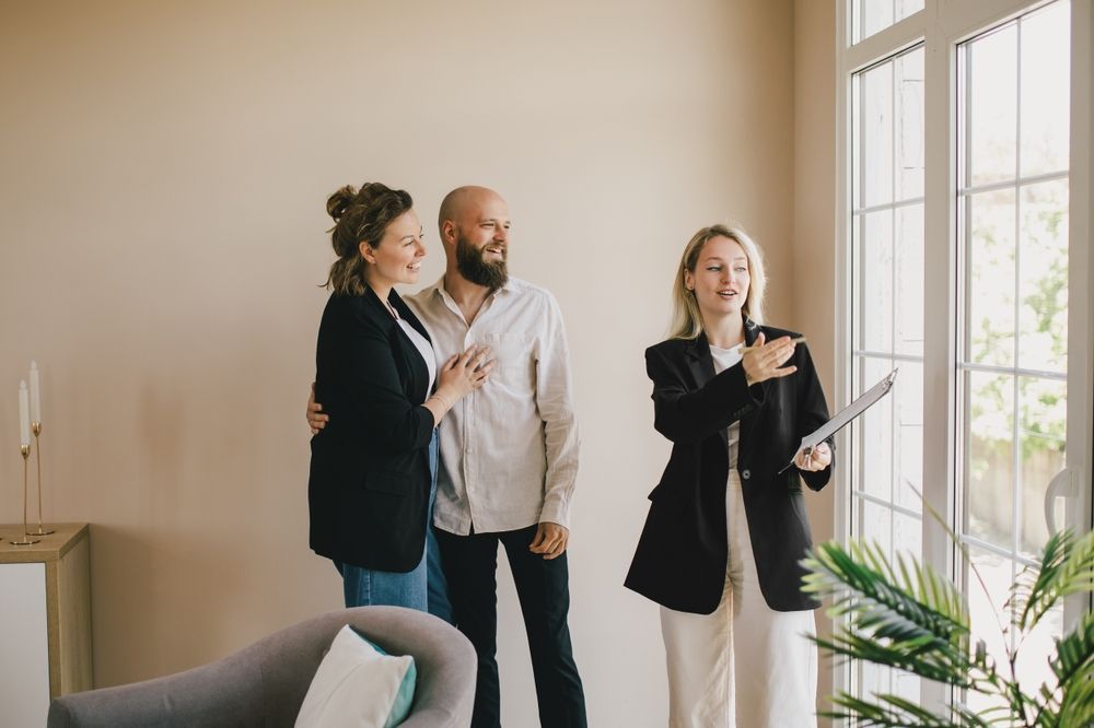 A Man And A Woman Are Standing Next To Each Other In A Living Room — Settle Petal Mobile Conveyancing In Wallabi Point, NSW