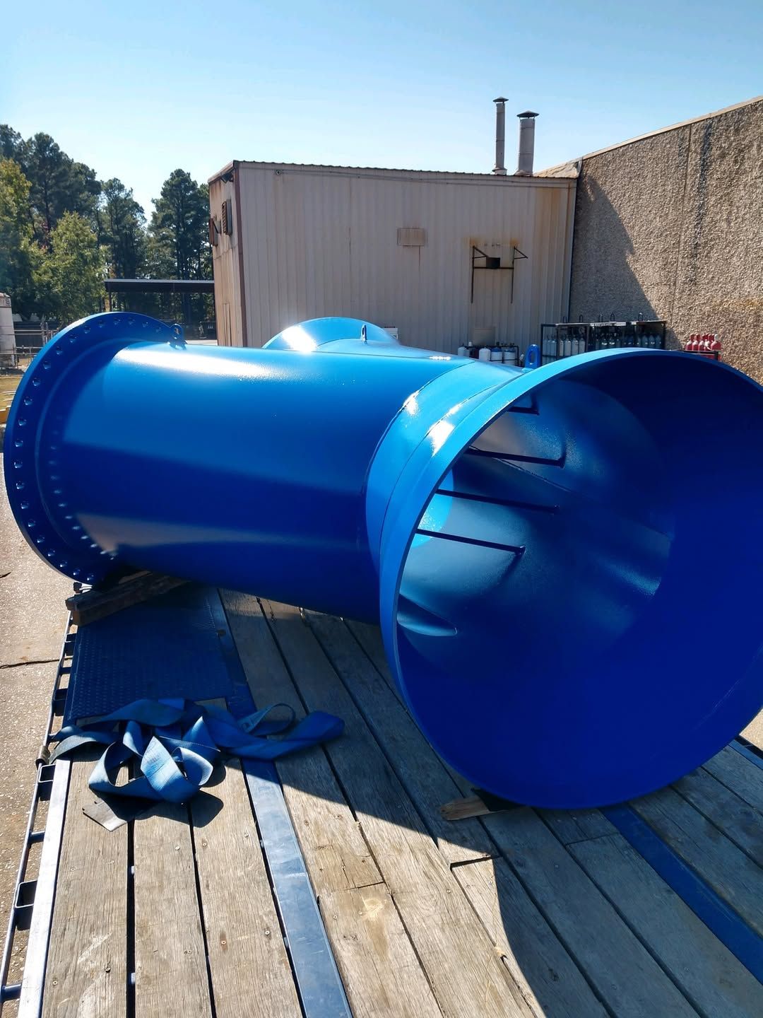A large blue pipe is sitting on a wooden deck in front of a building.