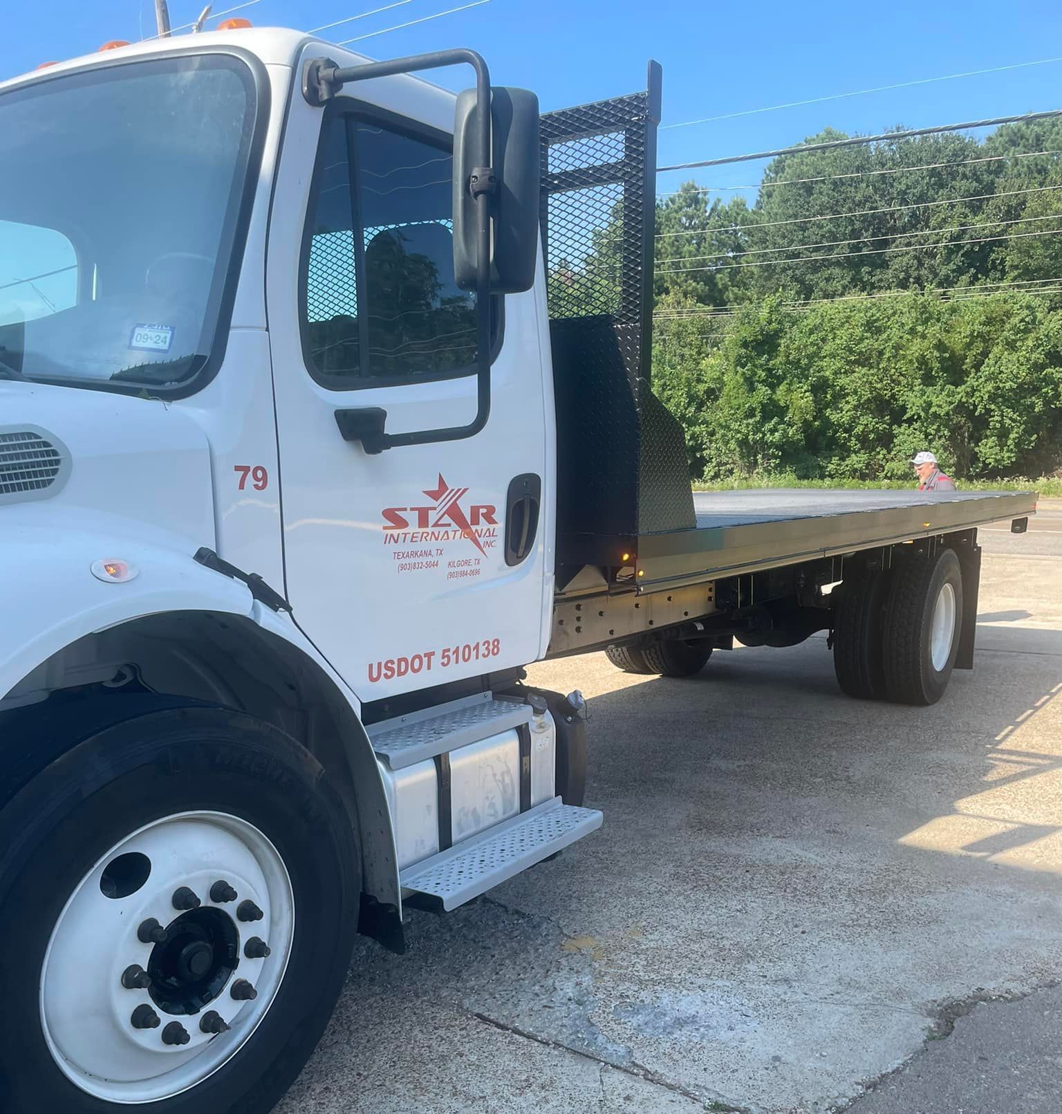 A white truck with the number 79 on the side is parked on the side of the road.