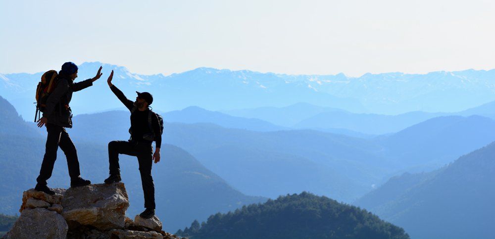 two hikers joyfully reaching the top of path