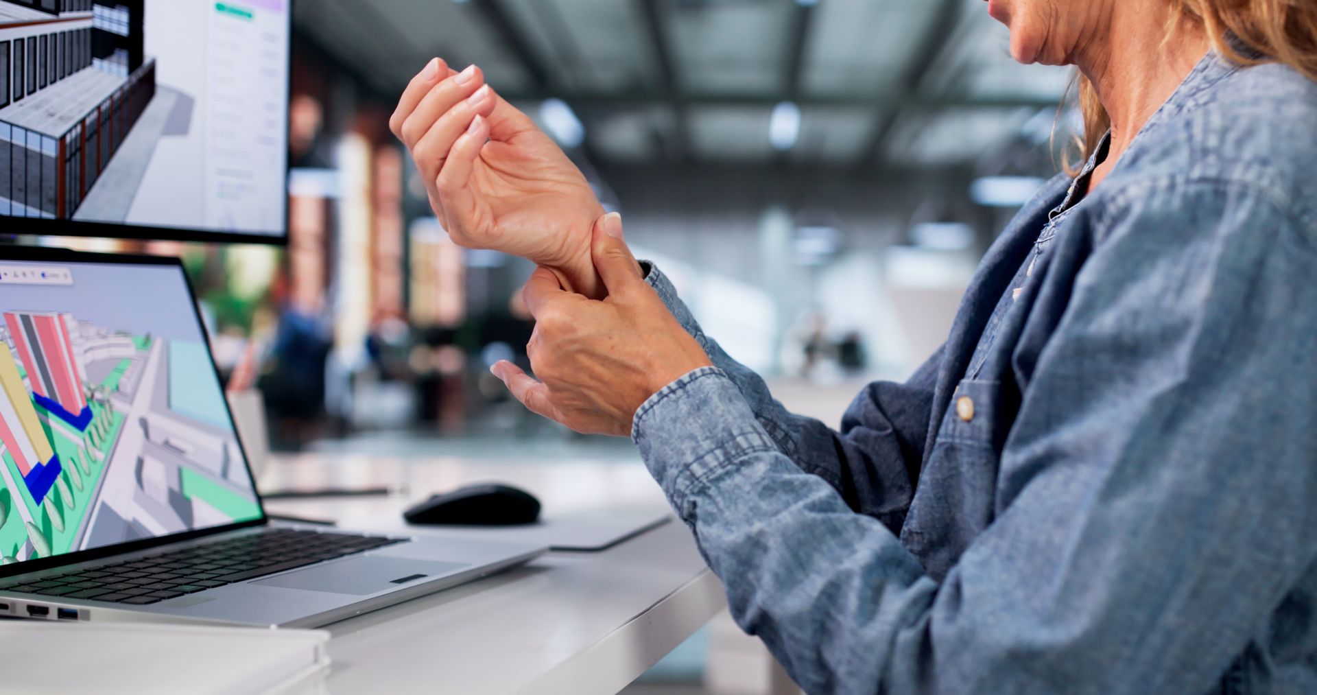 Person adjusting a wristband at a desk with laptop analytics on screen