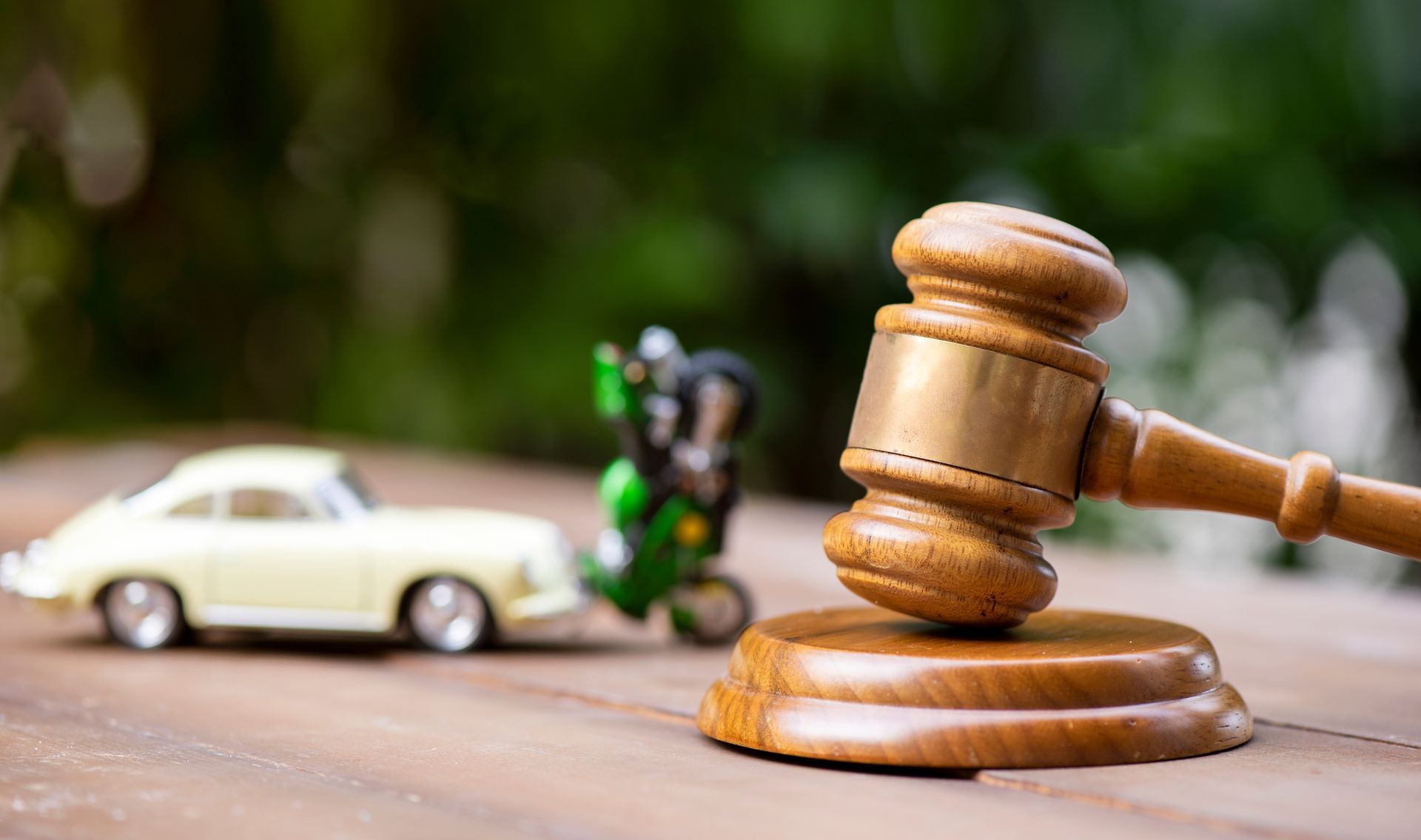 A judge's hammer with a car and motorbike collision in the background.