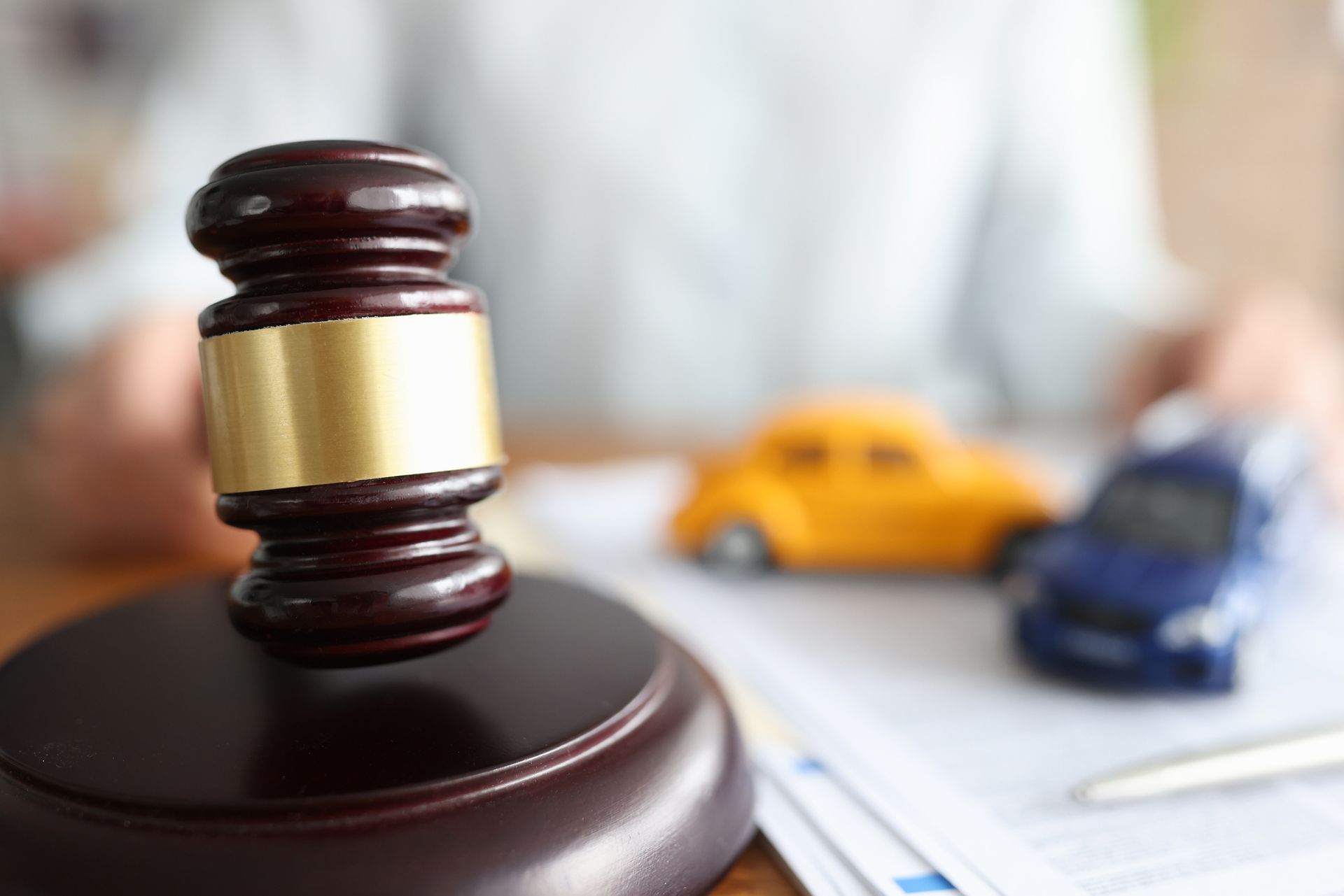 Judge’s gavel poised over toy cars symbolizing legal decisions in car accident cases.